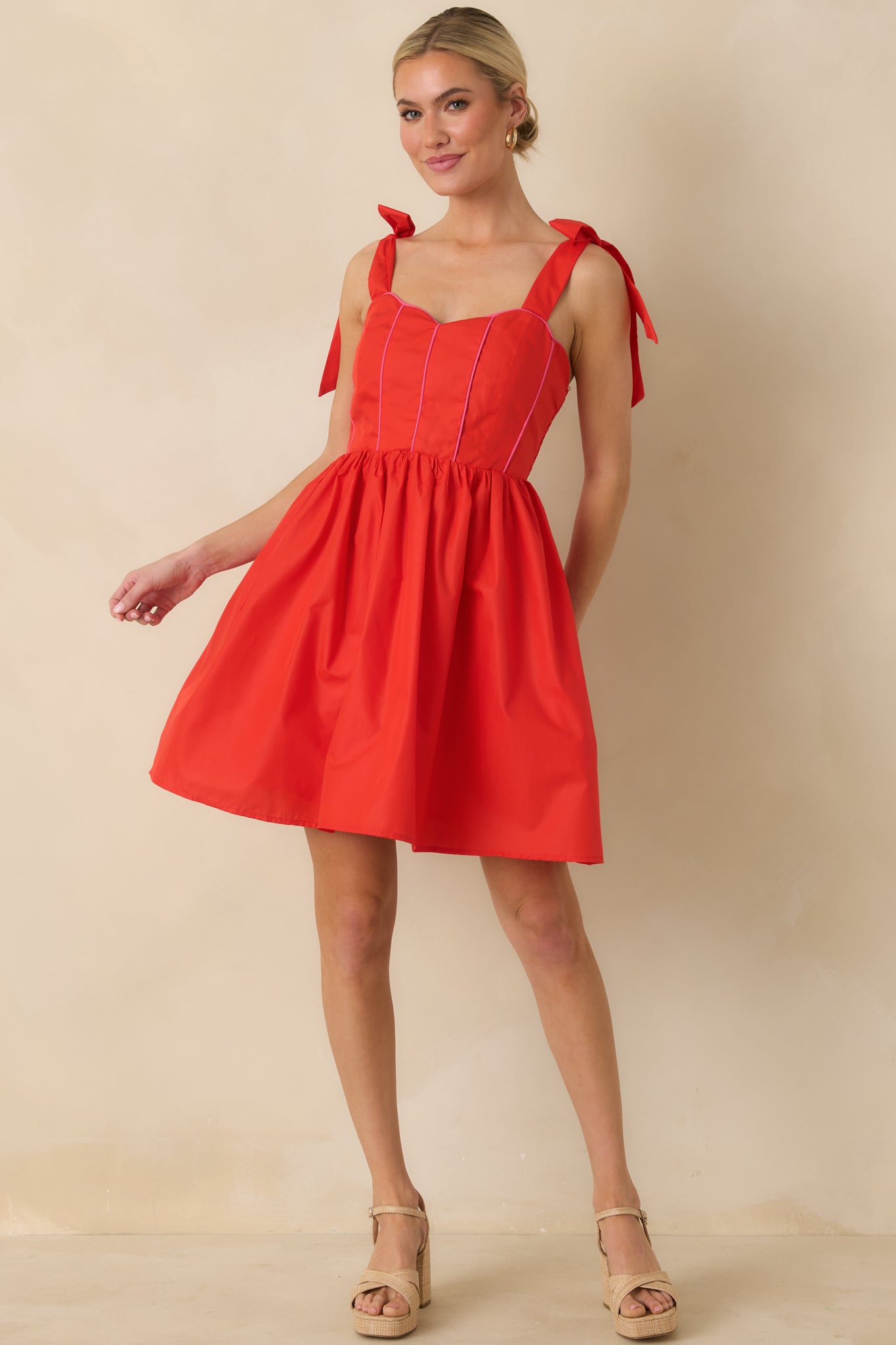 Angled front perspective highlighting the smocked back panel, functional pockets, and fitted bodice of the red mini dress.