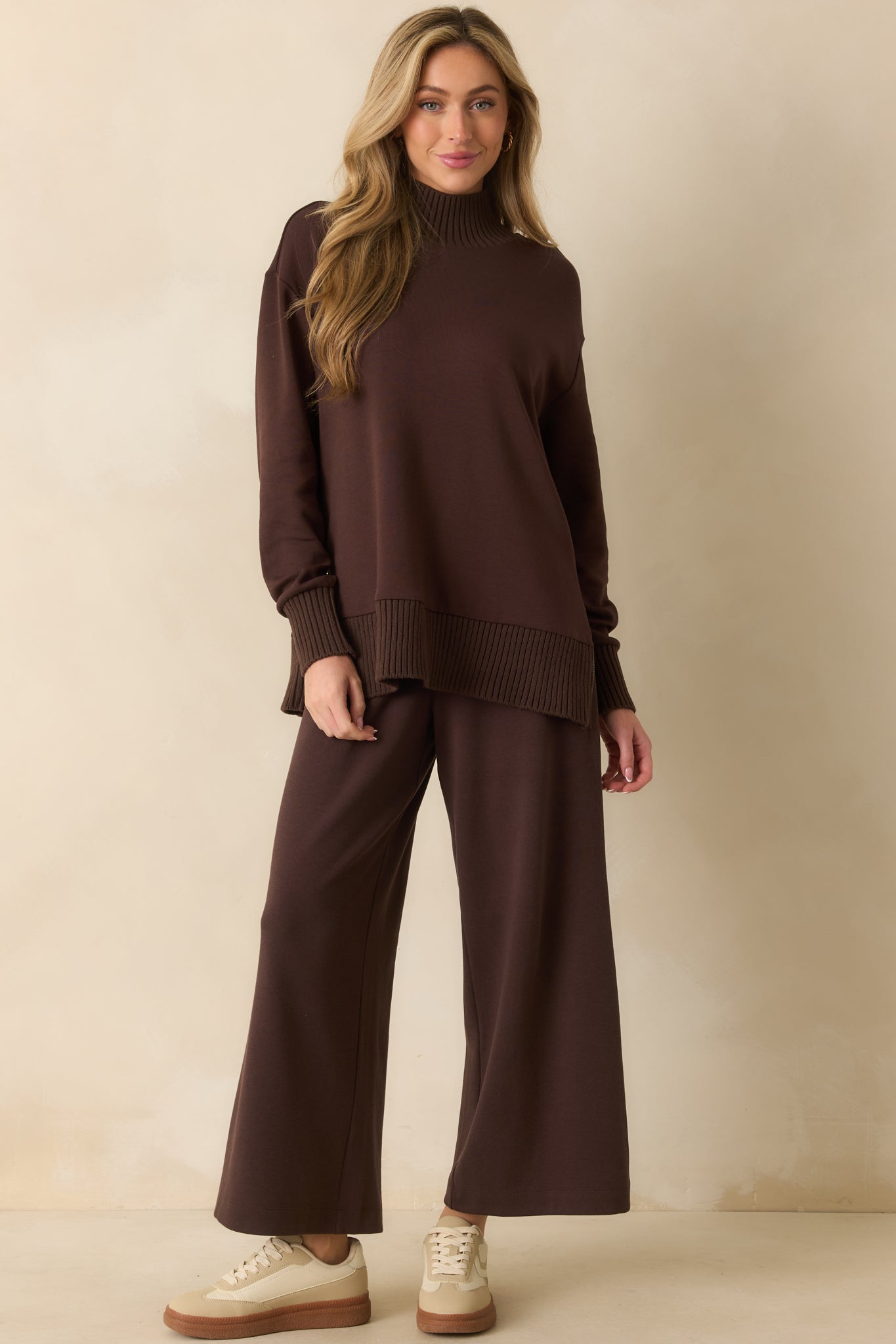 A front-facing angled view featuring ribbed cuffs, hem, and functional side zippers on the sweater.