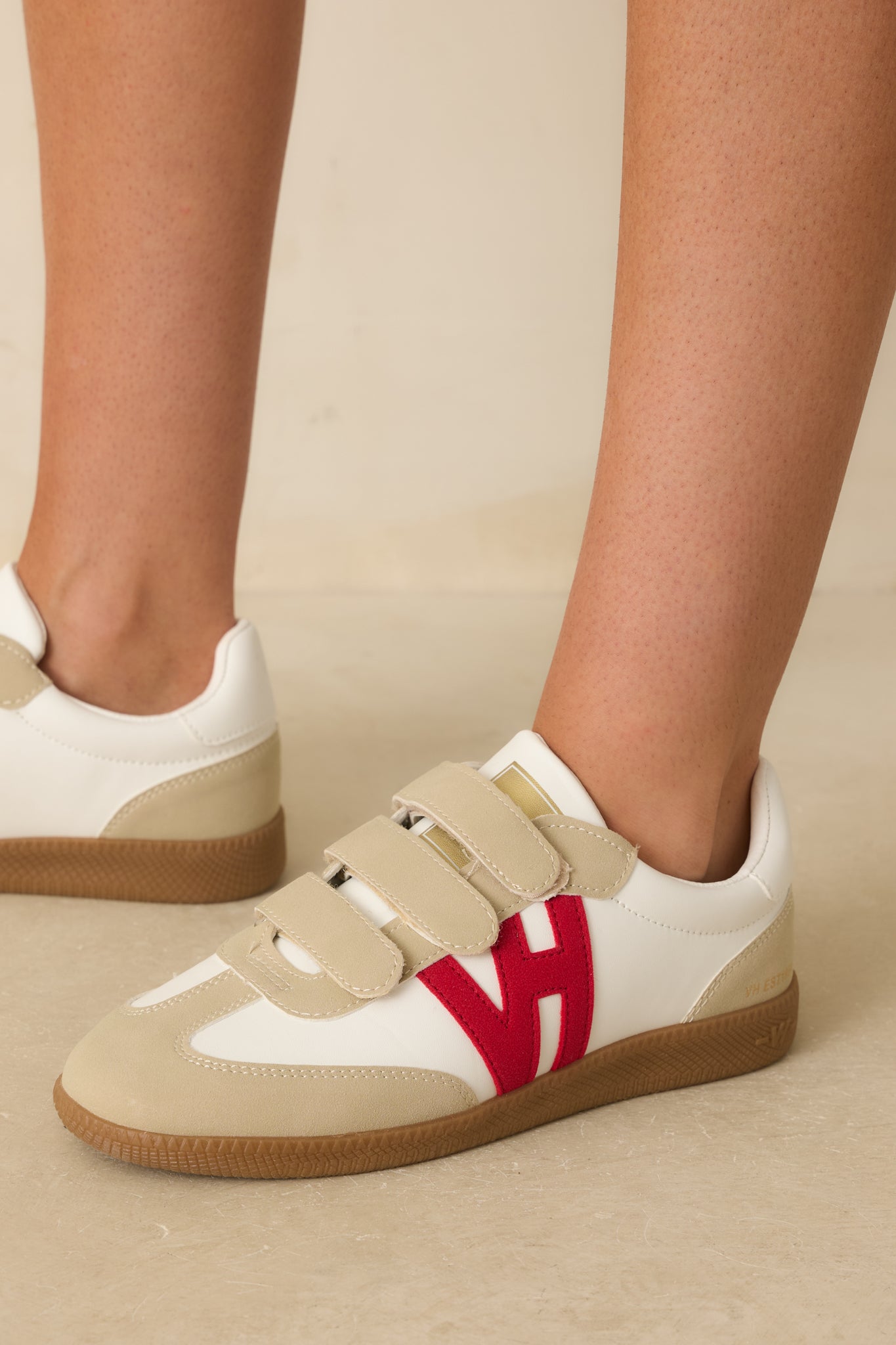 Angled sneaker view emphasizing the smooth ivory upper, beige suede accents, and classic brown rubber outsole with textured tread.