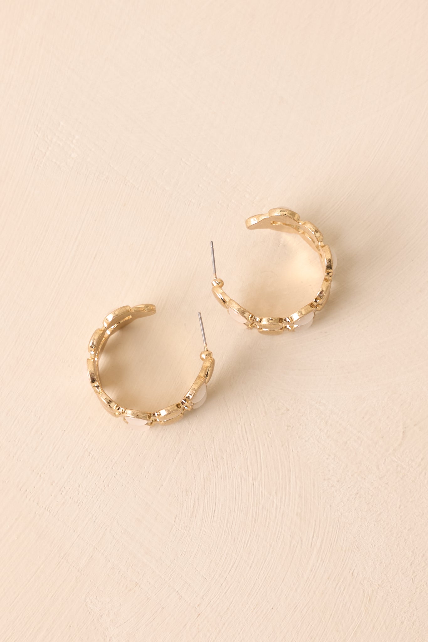 An angled shot highlighting the textured gold finish and alternating iridescent stones on the hoop earrings.