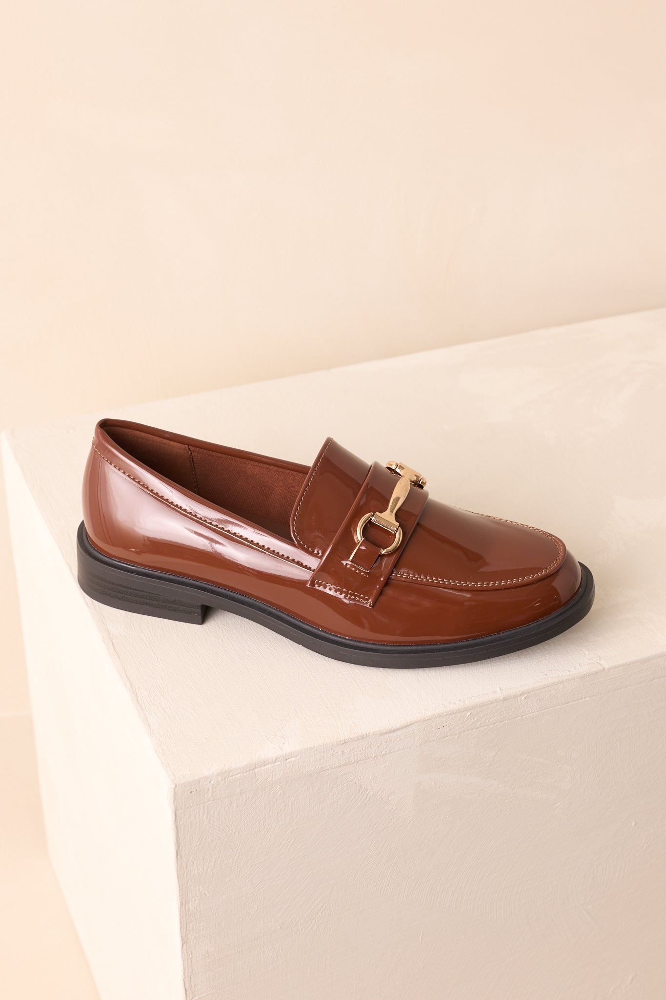 Angled view of glossy brown loafer showing horsebit accent.