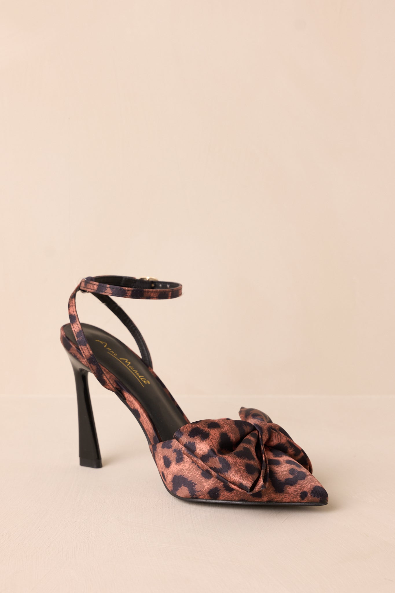 Angled view of the leopard print heels showing the pointed toe, bow embellishment, and patterned upper.