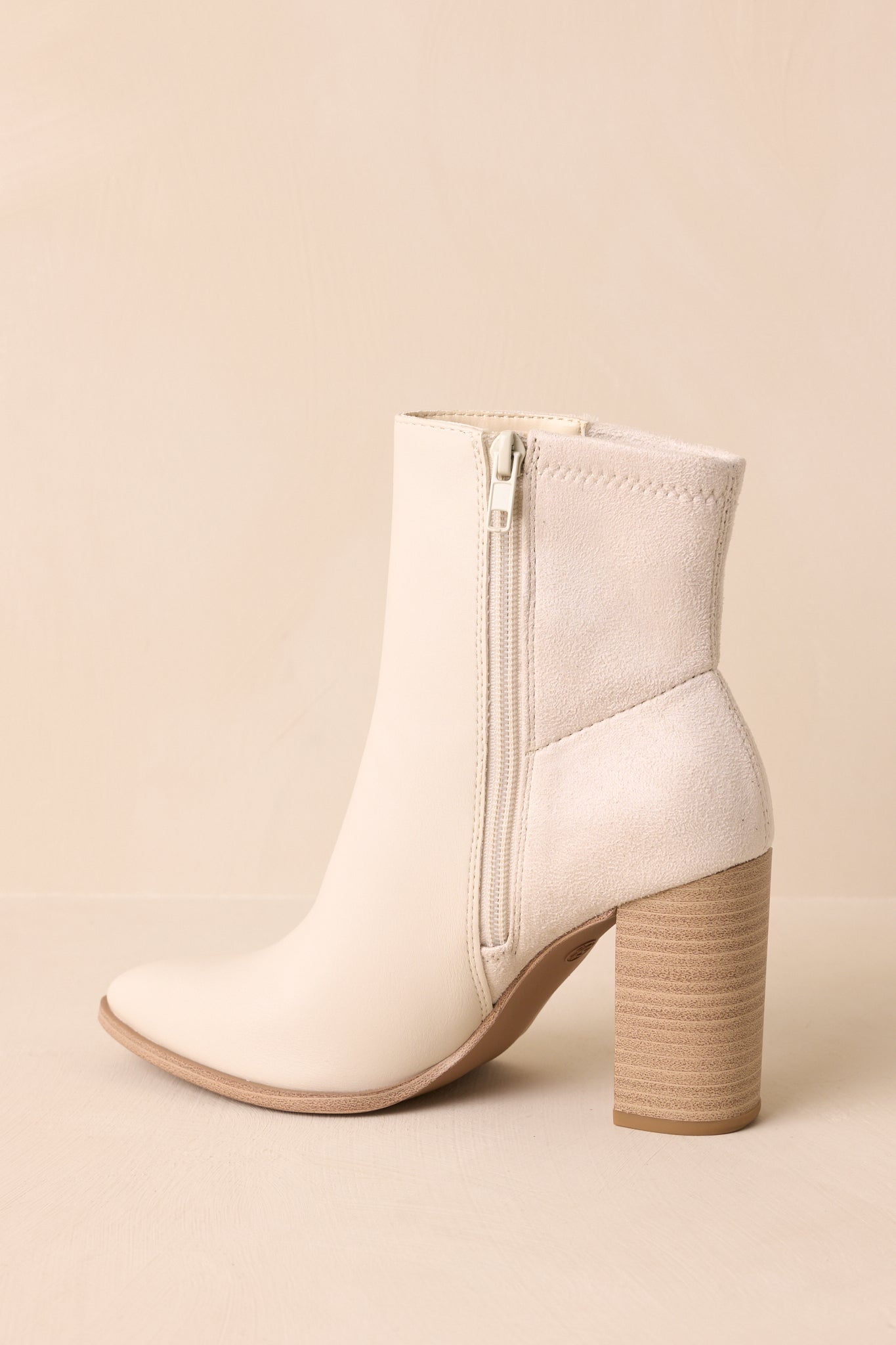 Angled view of the boots showcasing the inner side zipper closure and sleek pointed toe profile.