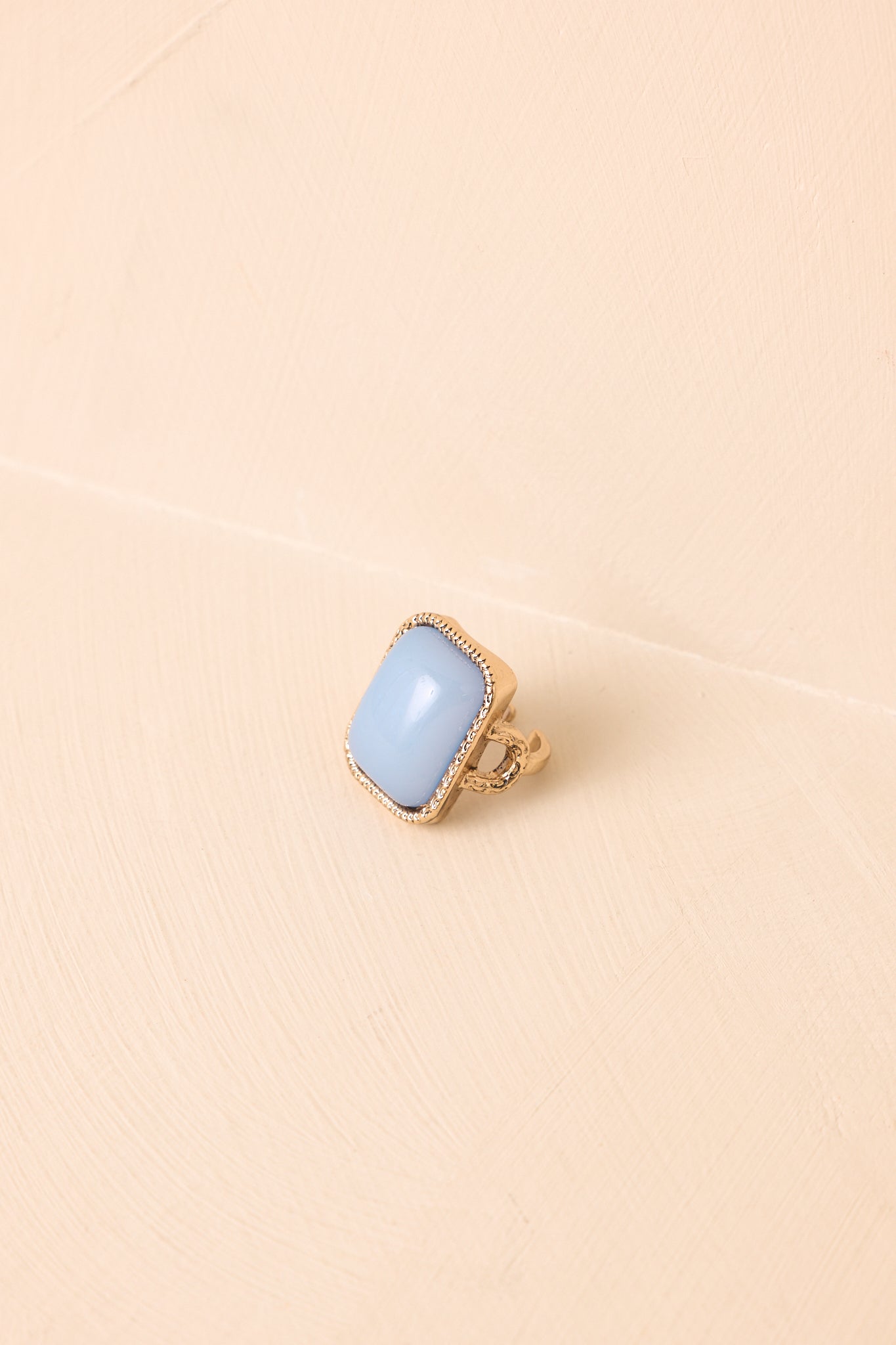 Antiqued gold-tone ring showcasing a smooth rectangular sky blue cabochon stone, beaded bezel detailing, and adjustable open-back band.