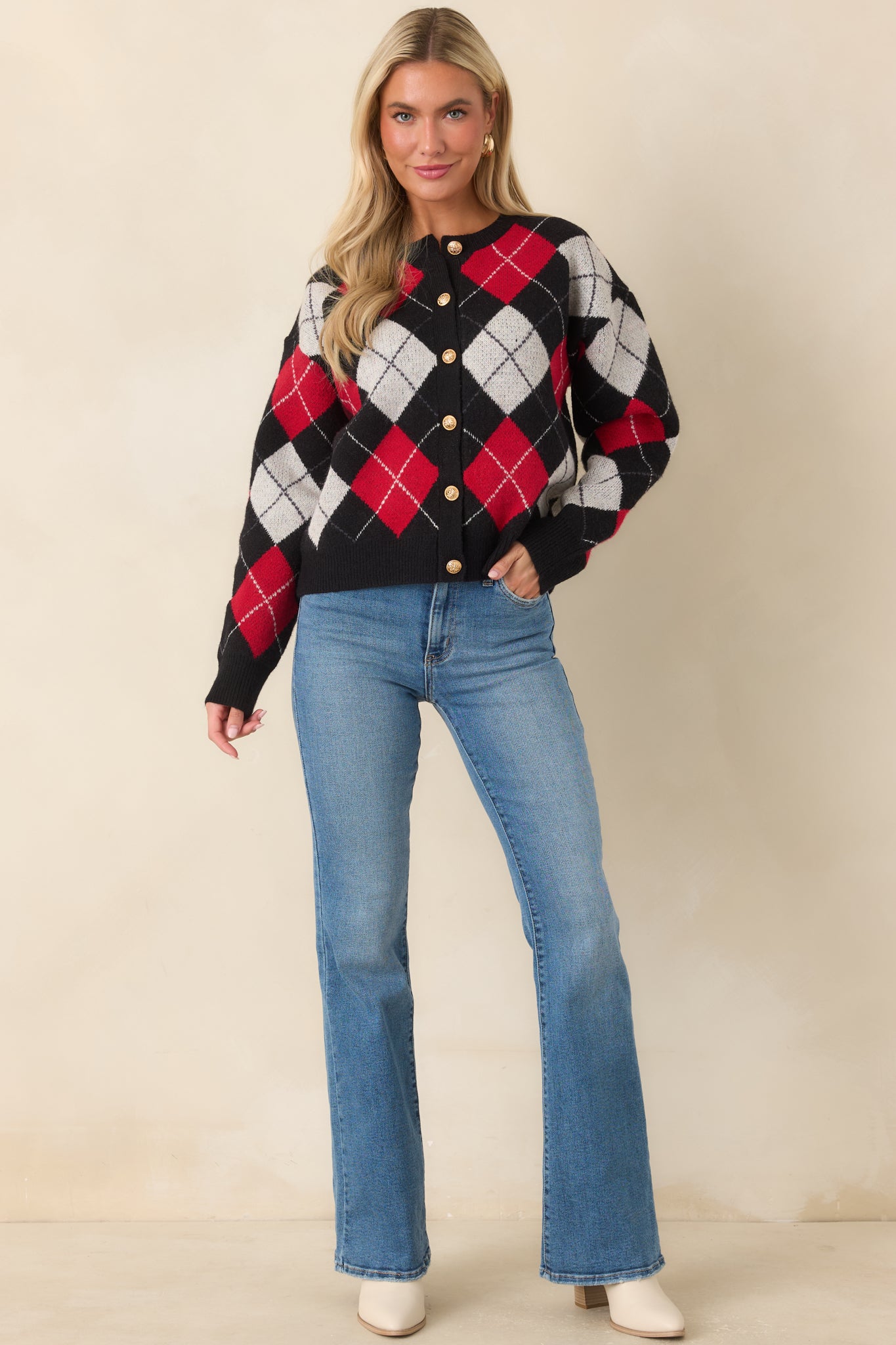 Argyle cardigan featuring black, red, and ivory diamond patterns, gold-tone buttons, and a relaxed silhouette.