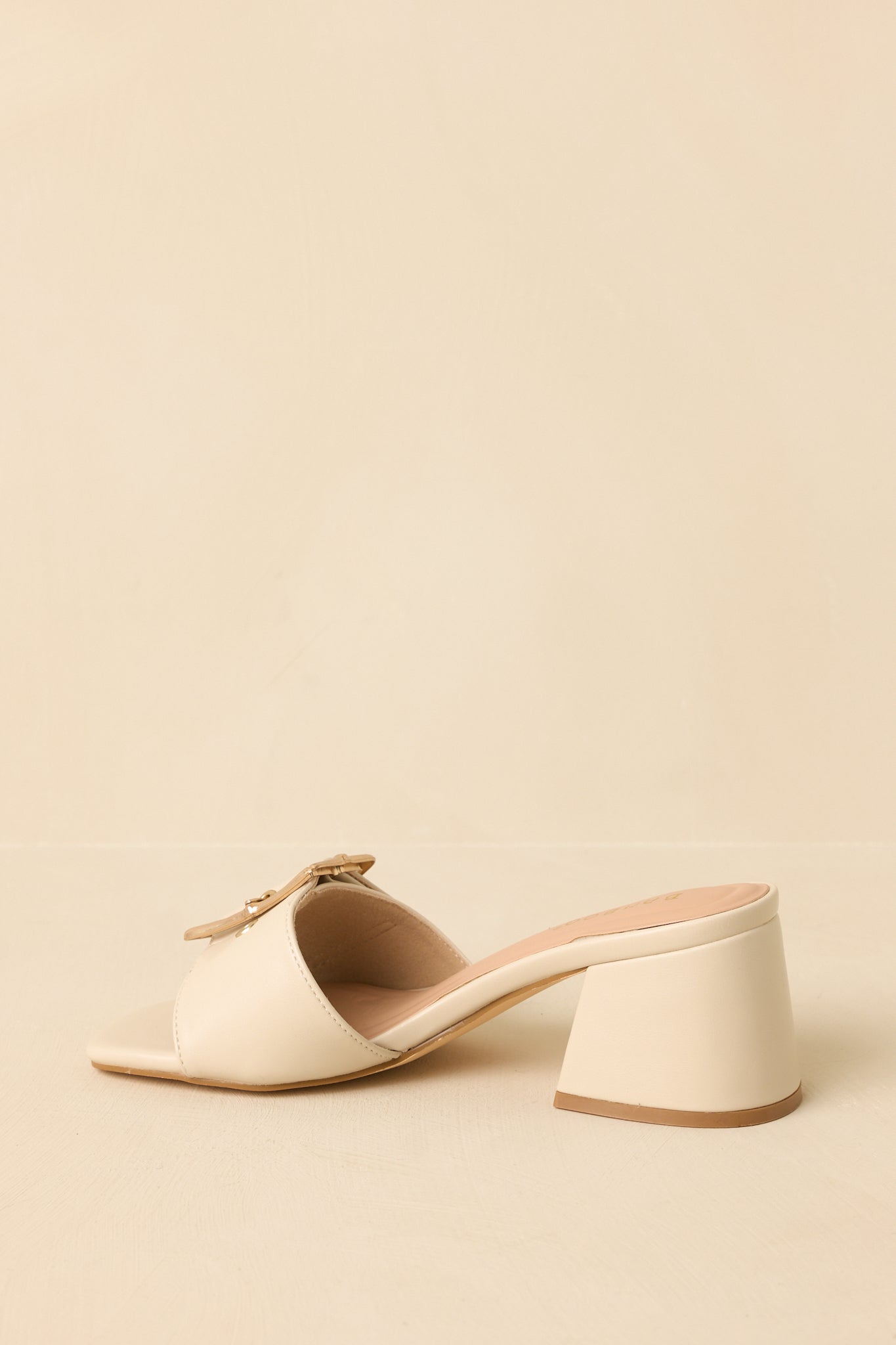Back view of the light beige block heels highlighting the open-back design and solid block heel support.