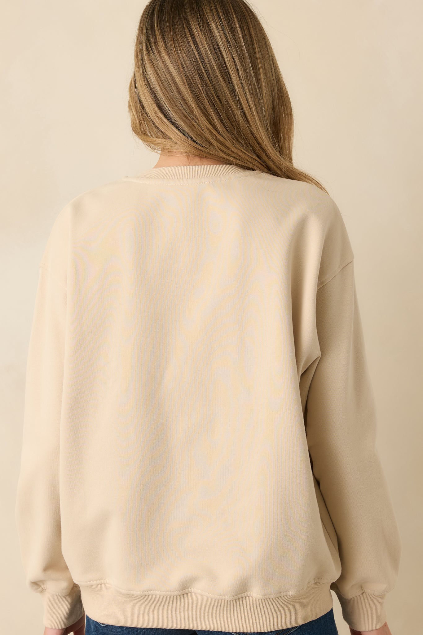 Back view of the light beige fleece sweatshirt highlighting the soft fleece fabric and ribbed trim.