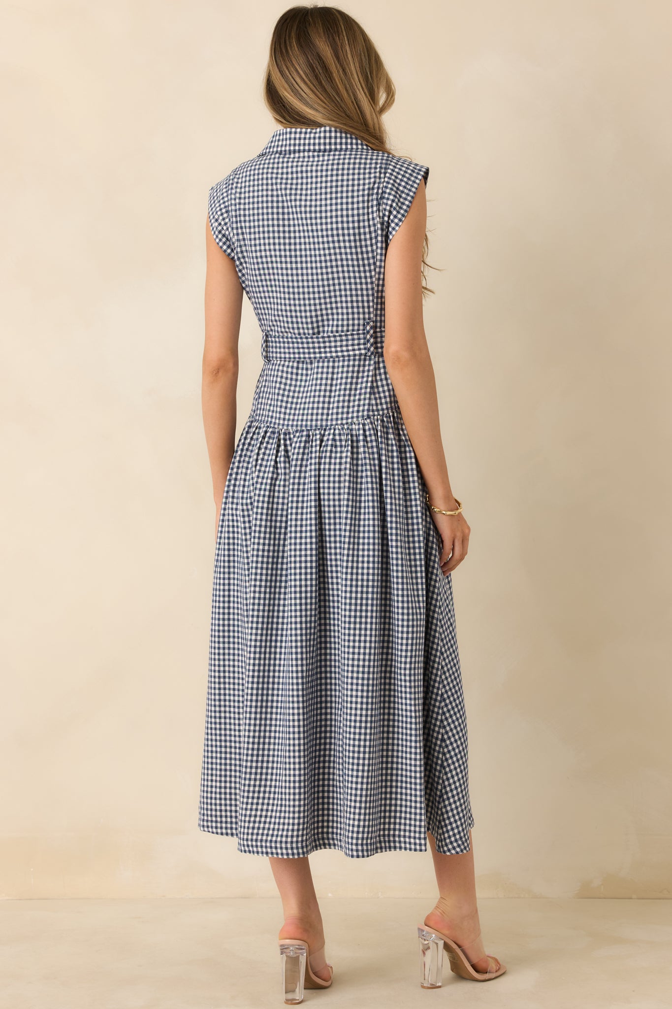 Back of the navy gingham midi dress highlighting a smooth back panel, gently gathered skirt, and clean hemline finish.