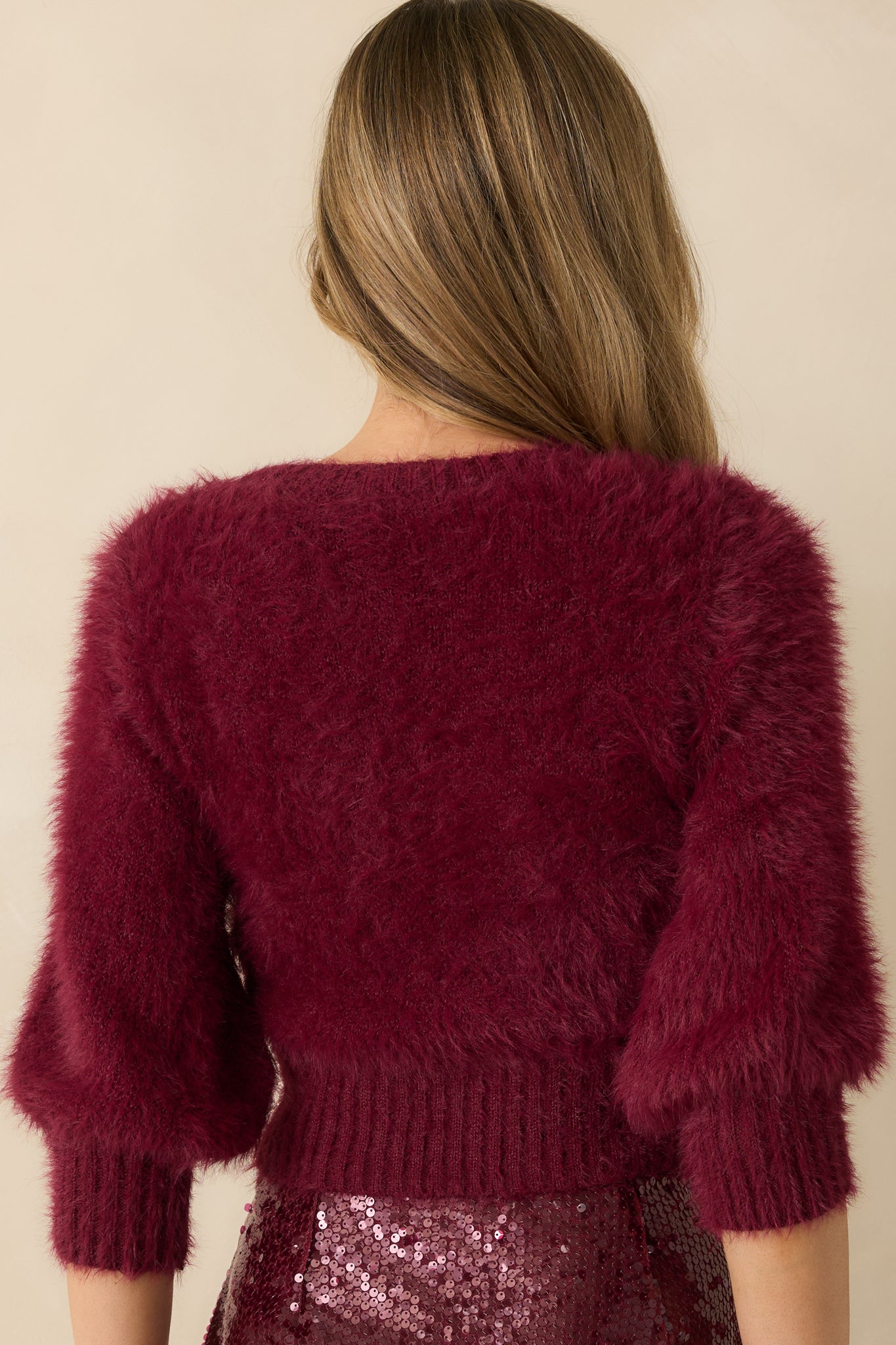 The back of the cropped sweater shows the plush knit texture, fitted hem, and short sleeves in a relaxed silhouette.