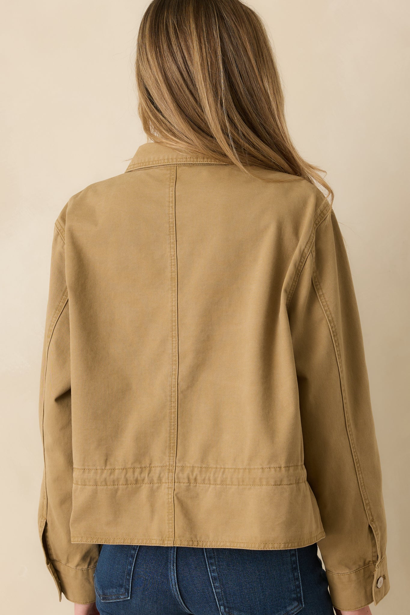 Back view of the tan utility jacket featuring the relaxed shape and adjustable hem.