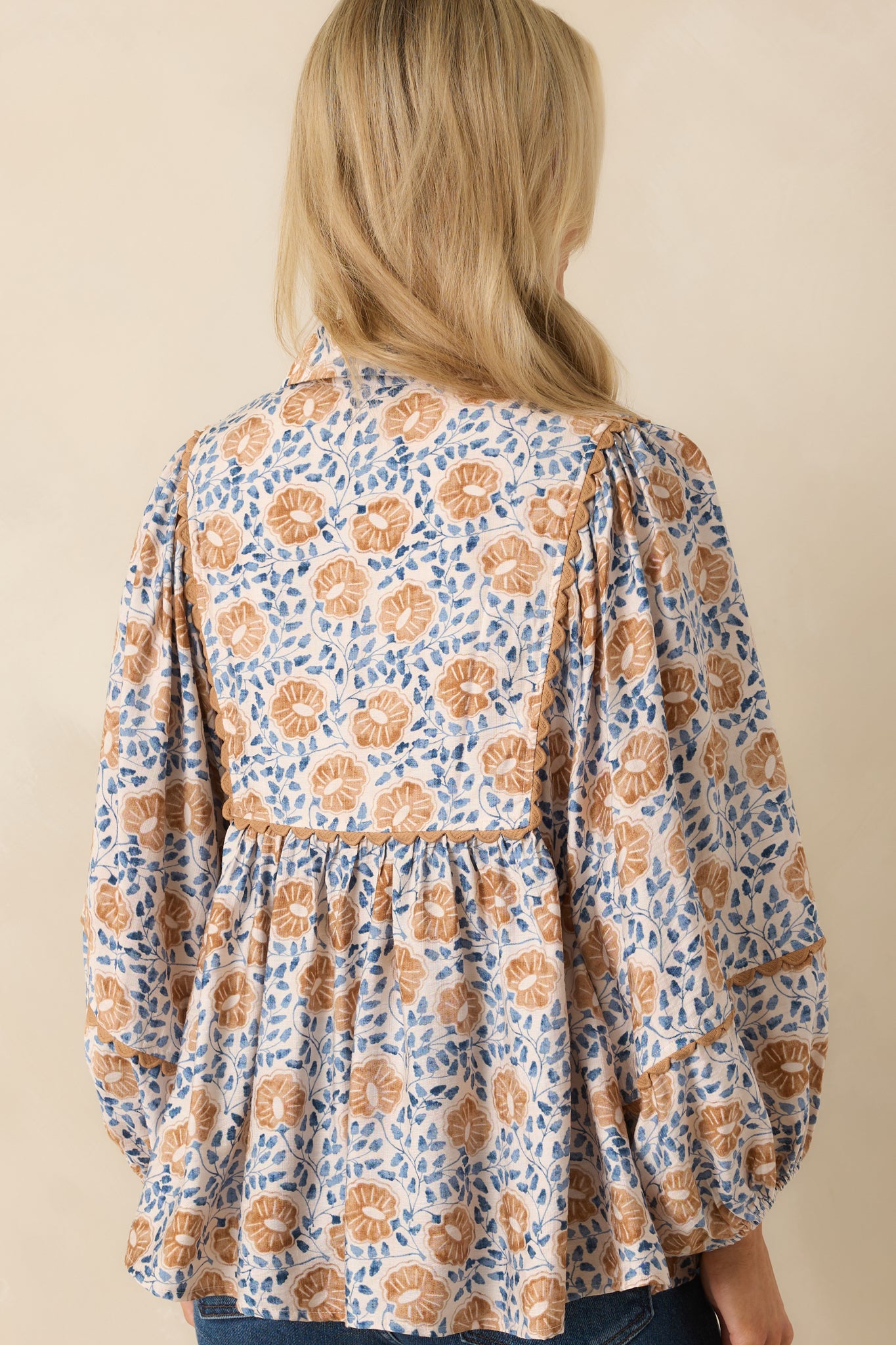 Back view of the top showing the continuation of the floral print and the relaxed fit with long sleeves.