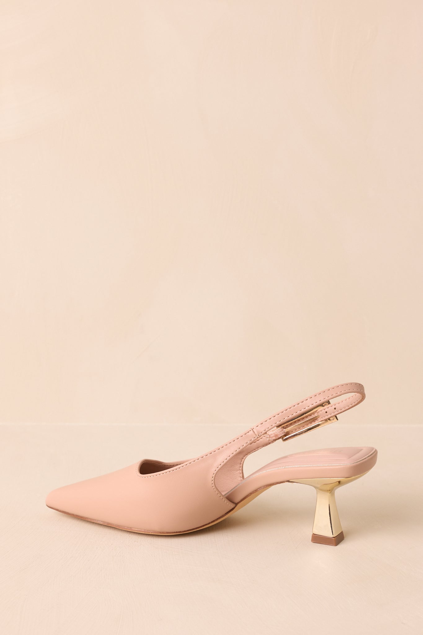 Rear view of beige heels highlighting the slingback strap and gold kitten heel.