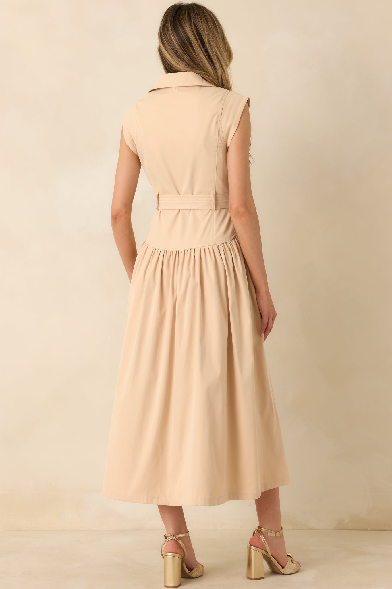 Back view of the beige midi shirt dress showing the gathered skirt and defined waistline.