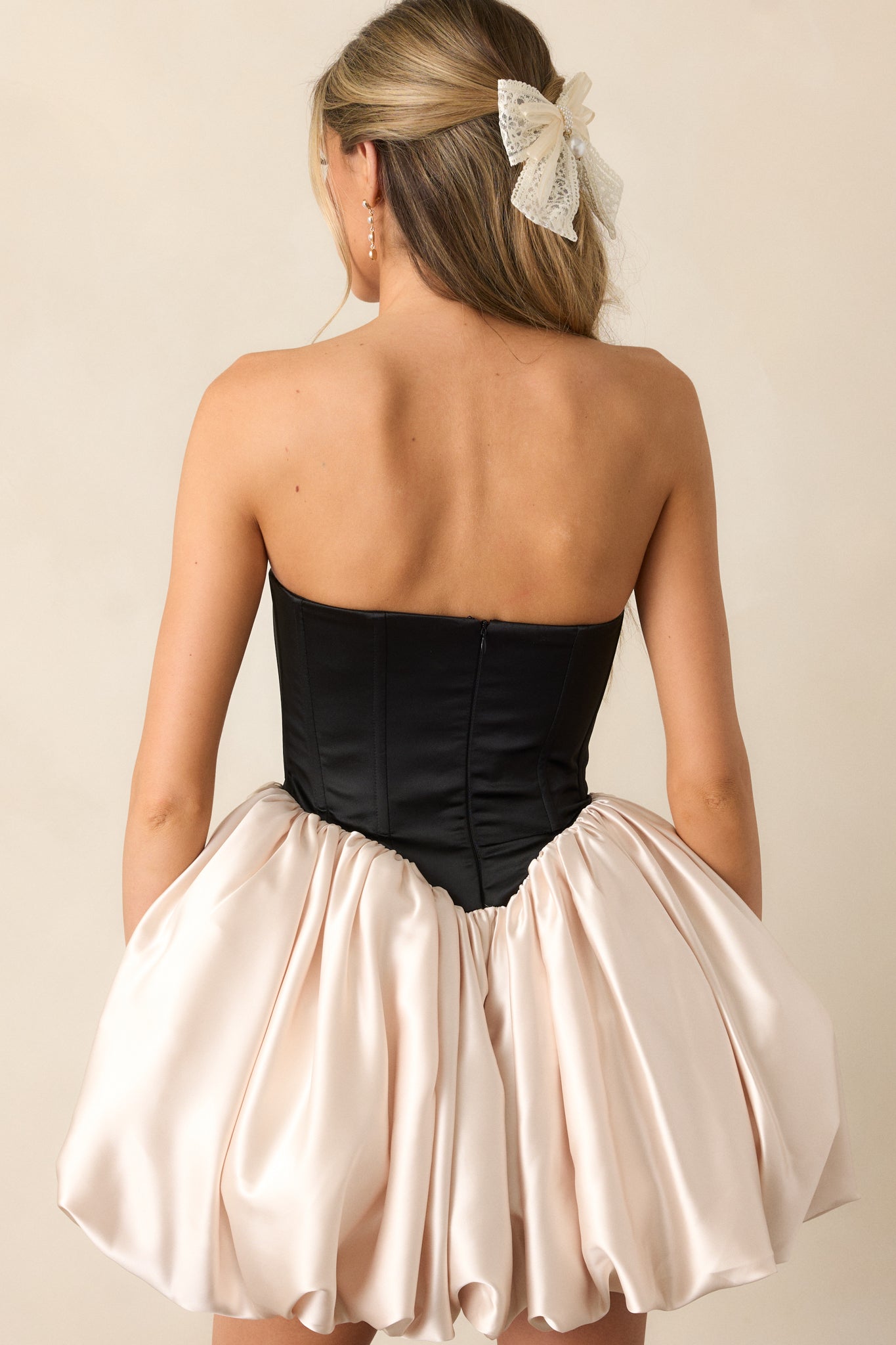 A complete back view of the dress, displaying the structured fit of the black corset and the elegant drape of the bubble skirt.