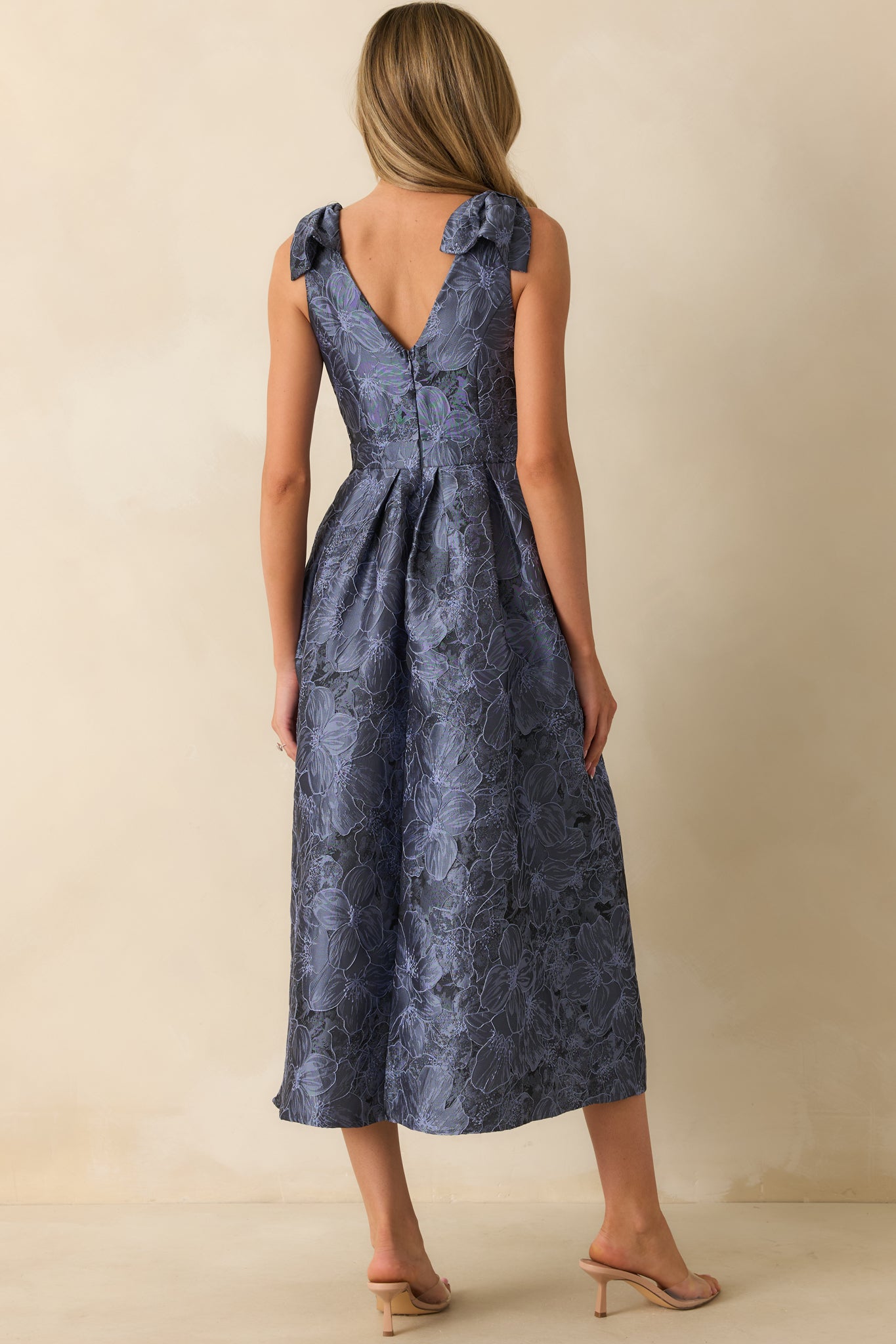 Rear view of blue floral midi dress showing discrete back zipper, bow straps, and sleeveless design.
