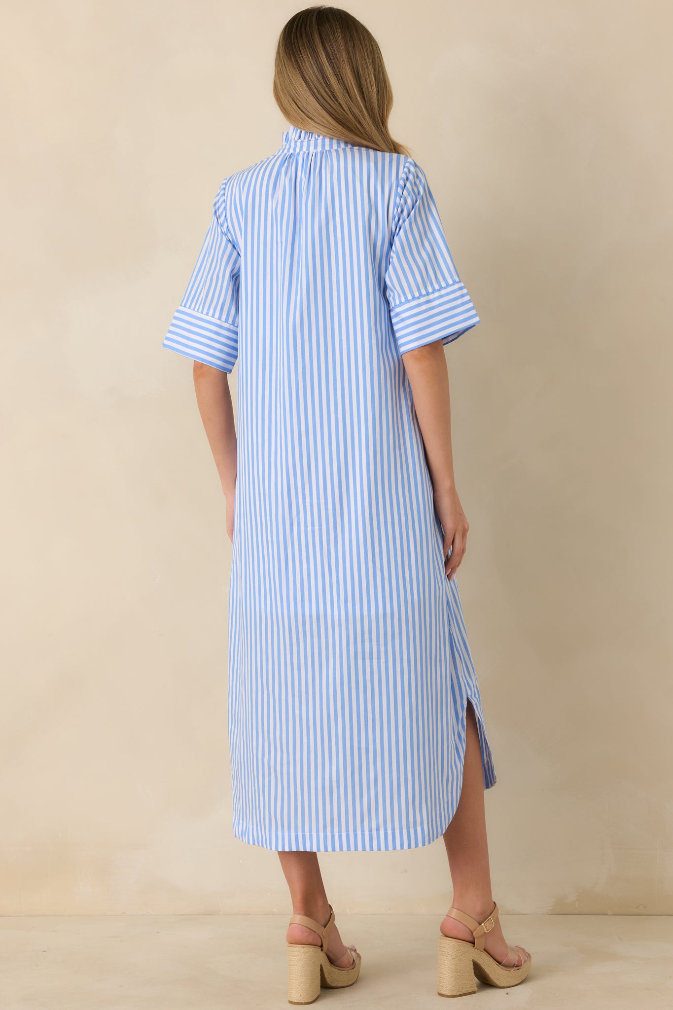 Back view of blue striped midi shirt dress highlighting the flowy skirt and shirttail hemline.