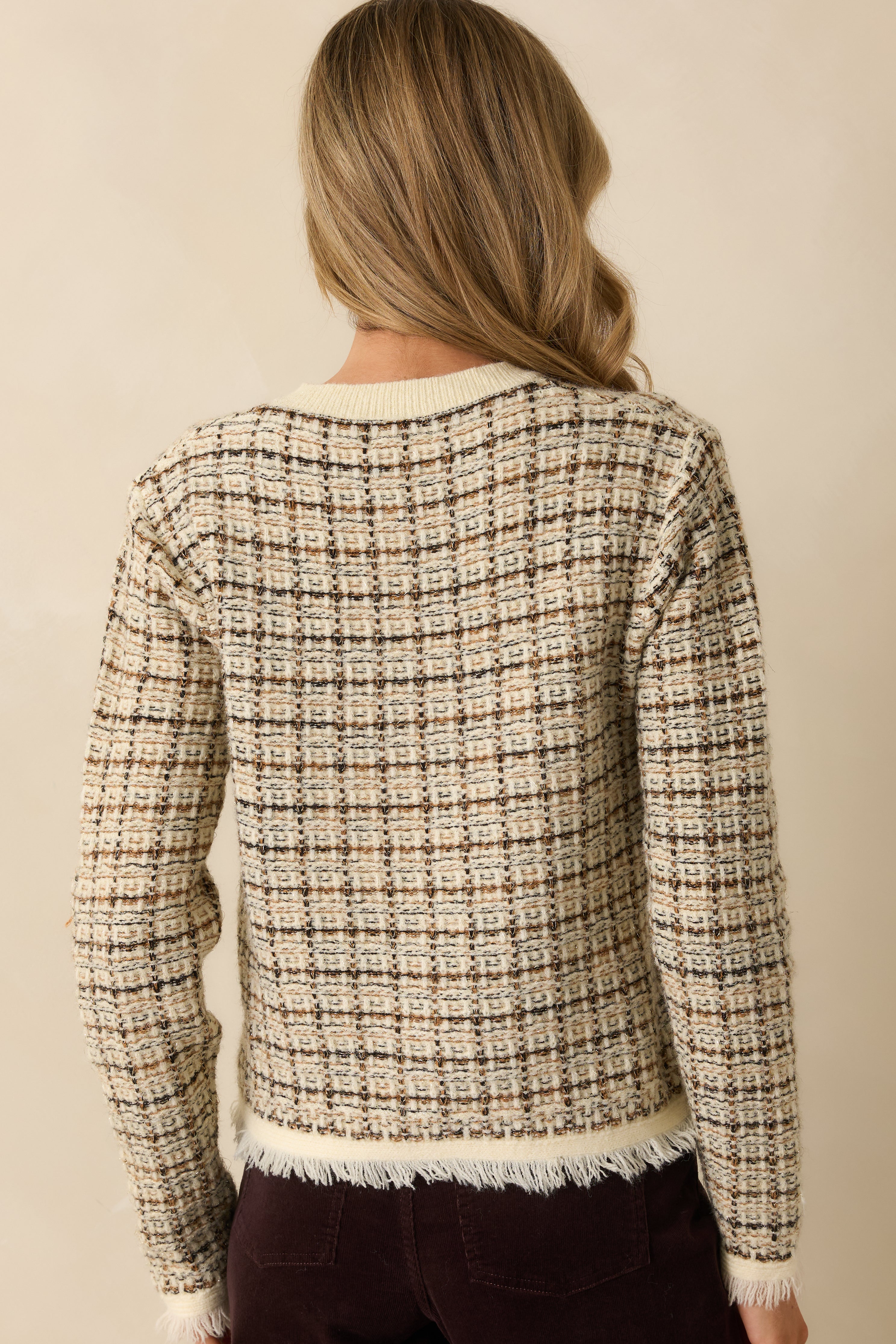 Back view of the cardigan and its woven plaid pattern in black, caramel, and gold.