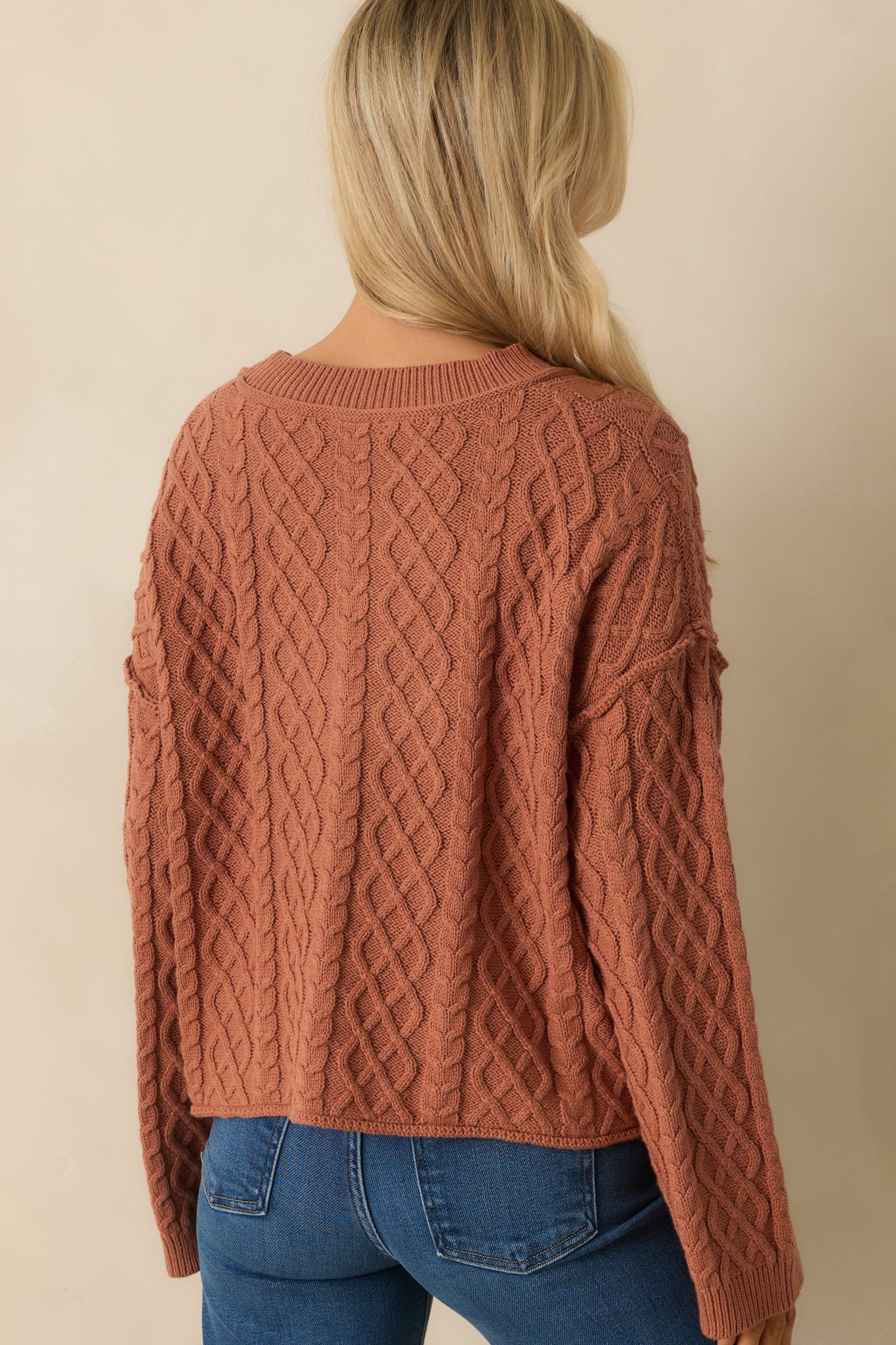 A back view of the cardigan showing the cable knit design and long sleeve structure.