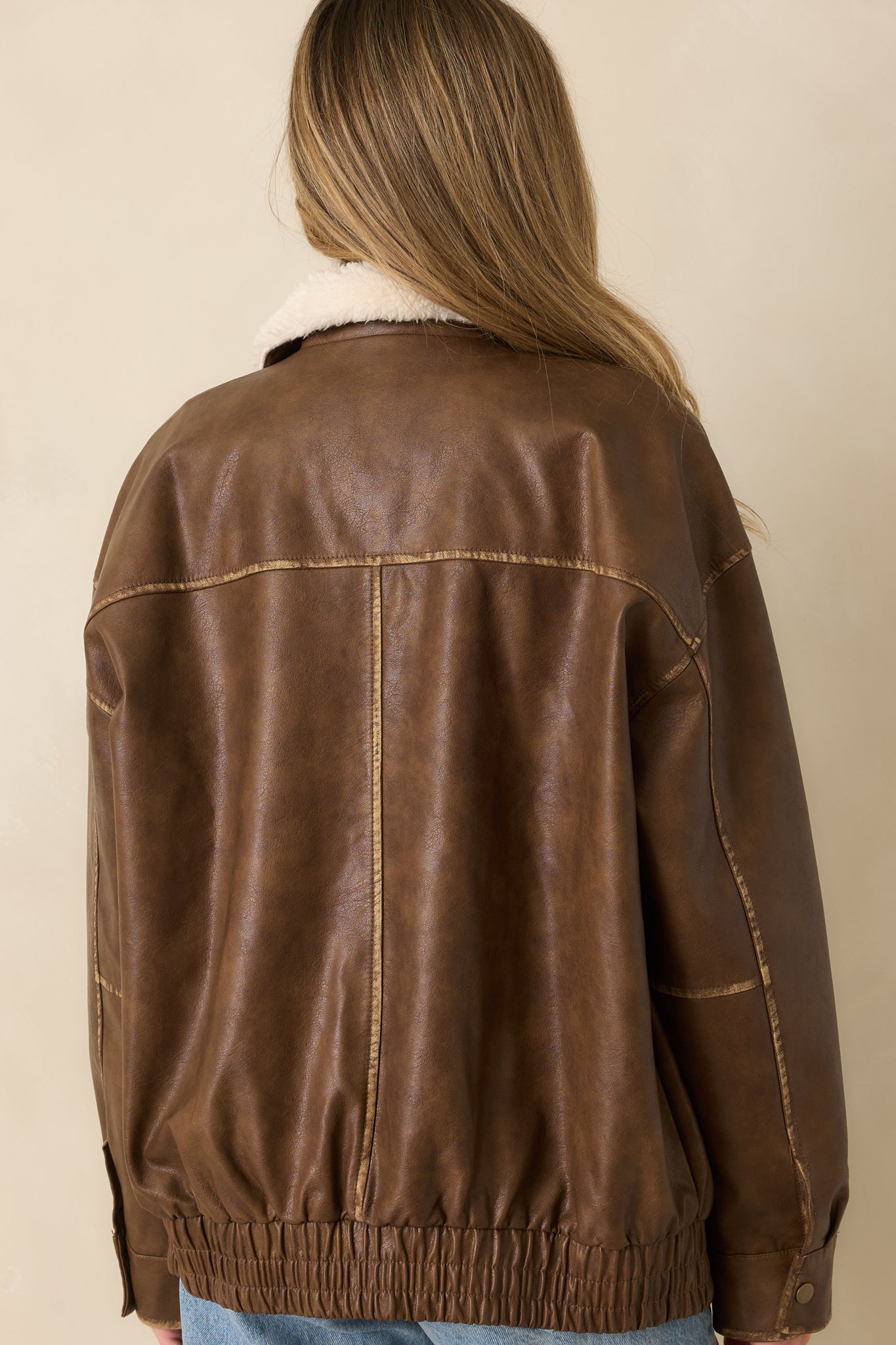 Back view of the cognac faux leather bomber jacket displaying its relaxed fit and elasticized hem.