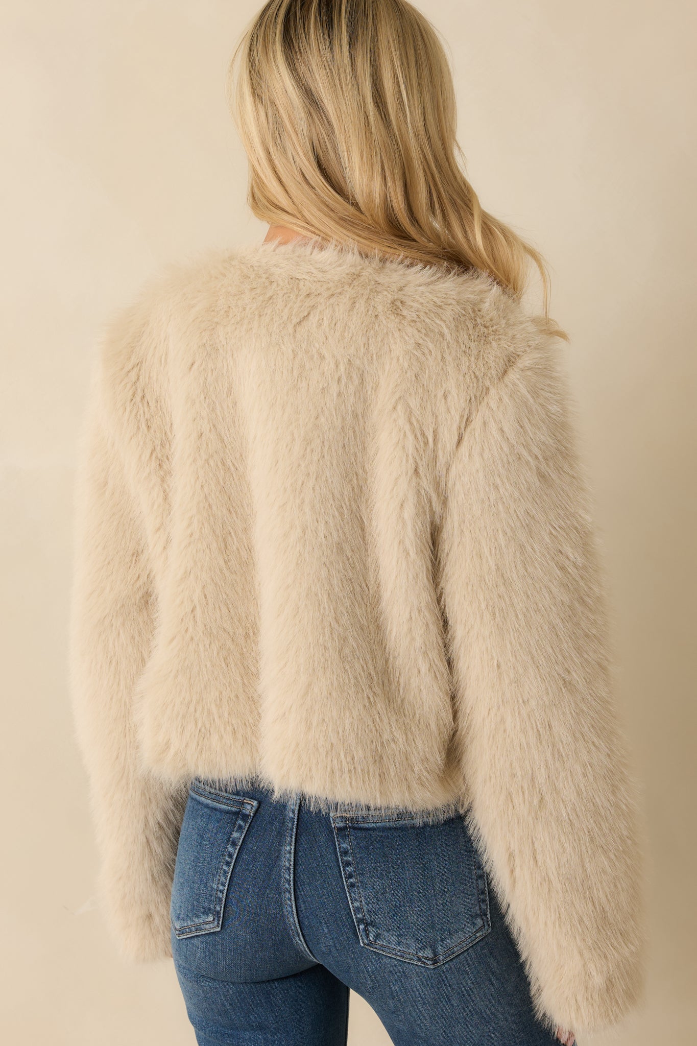 Back view of the cream cropped faux fur jacket displaying the plush fabric and relaxed fit.