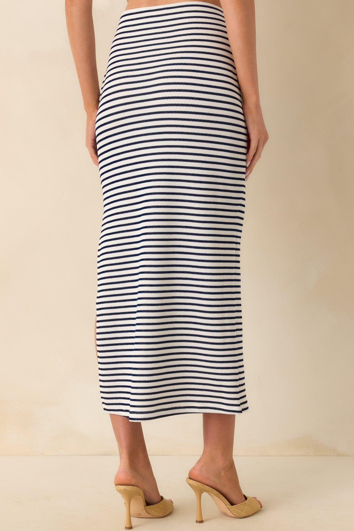 A back view displaying the elastic waist fit, vertical stripe alignment, and the smooth fall of the knit fabric to midi length.