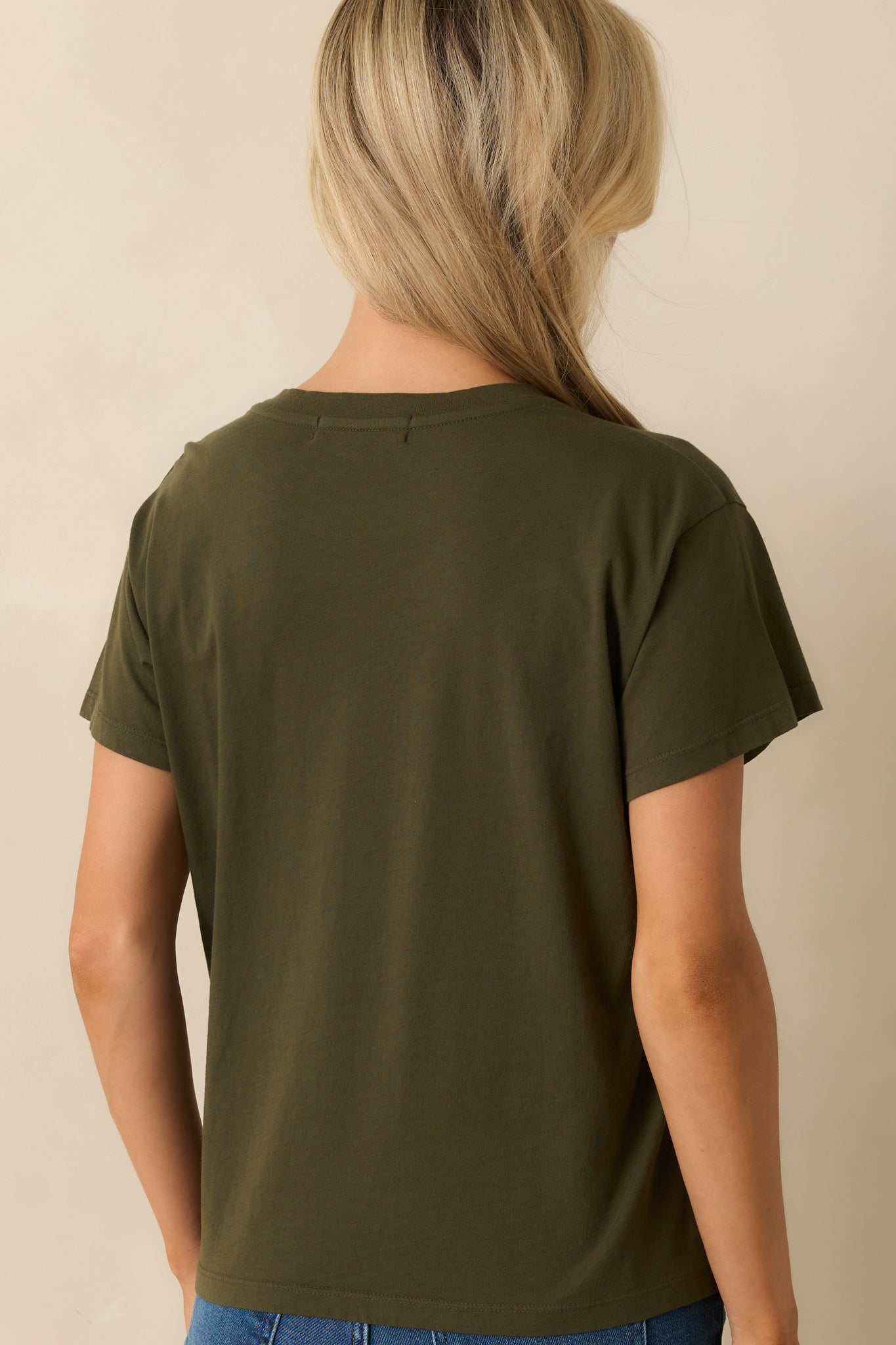 A back view of the tee displaying the plain army green cotton fabric and straight hem.