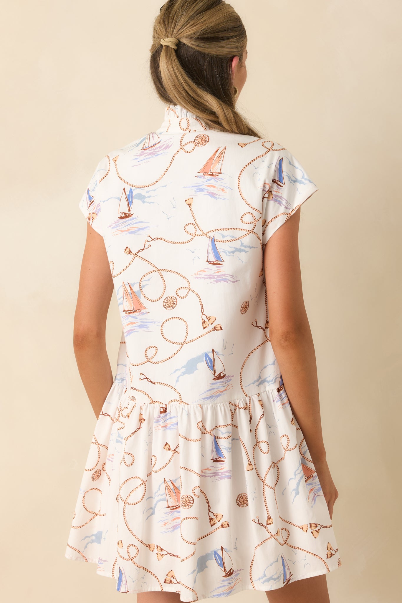 Back view of the mini dress featuring cap sleeves, a relaxed drop-waist shape, and gathered skirt detail.