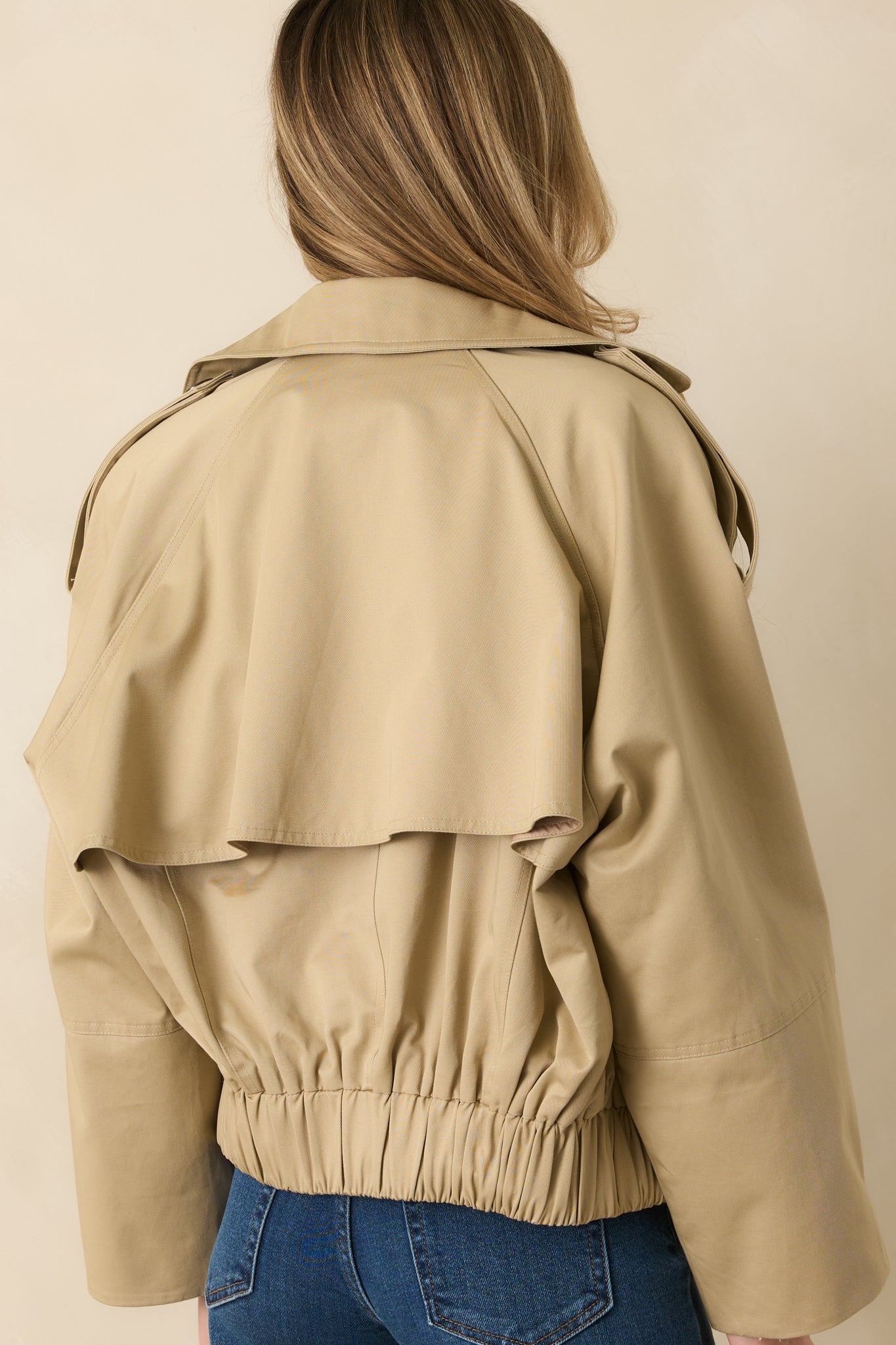 Back view displaying elasticized back hem, long sleeves, and cropped cotton silhouette.