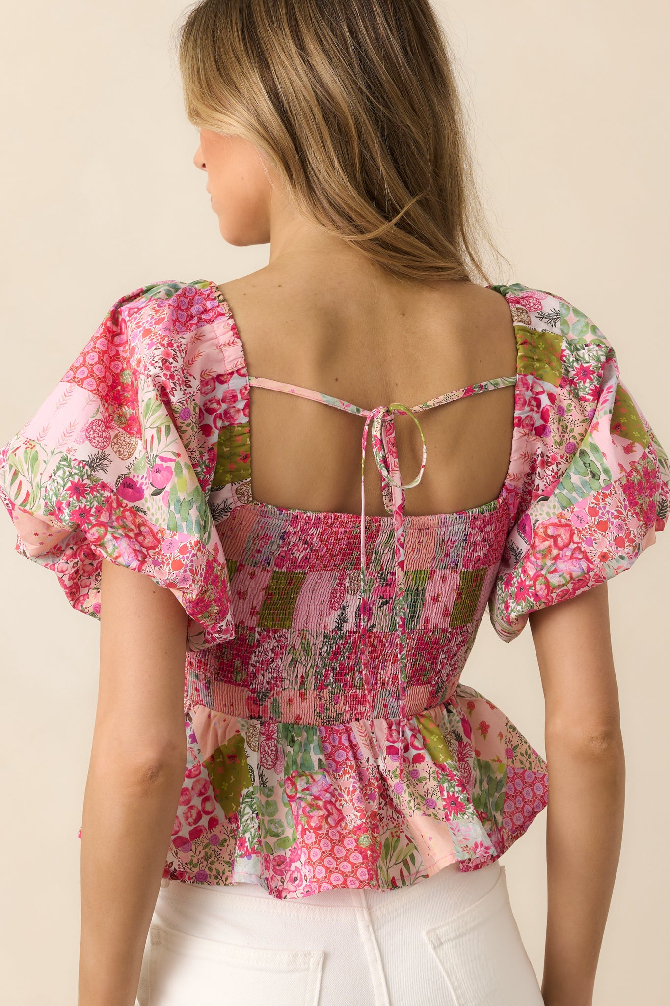 The back view of this pink top features a self-tie detail and flowing peplum hem for an adjustable and stylish fit.