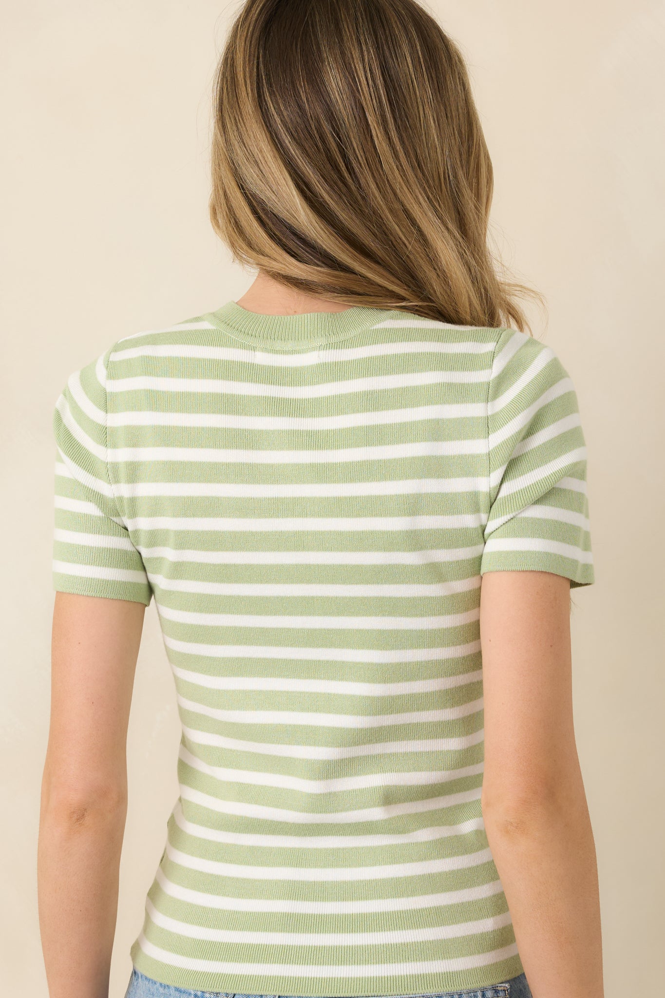 Back view of light green and ivory striped short sleeve knit top featuring a fitted silhouette and continuous stripe pattern.