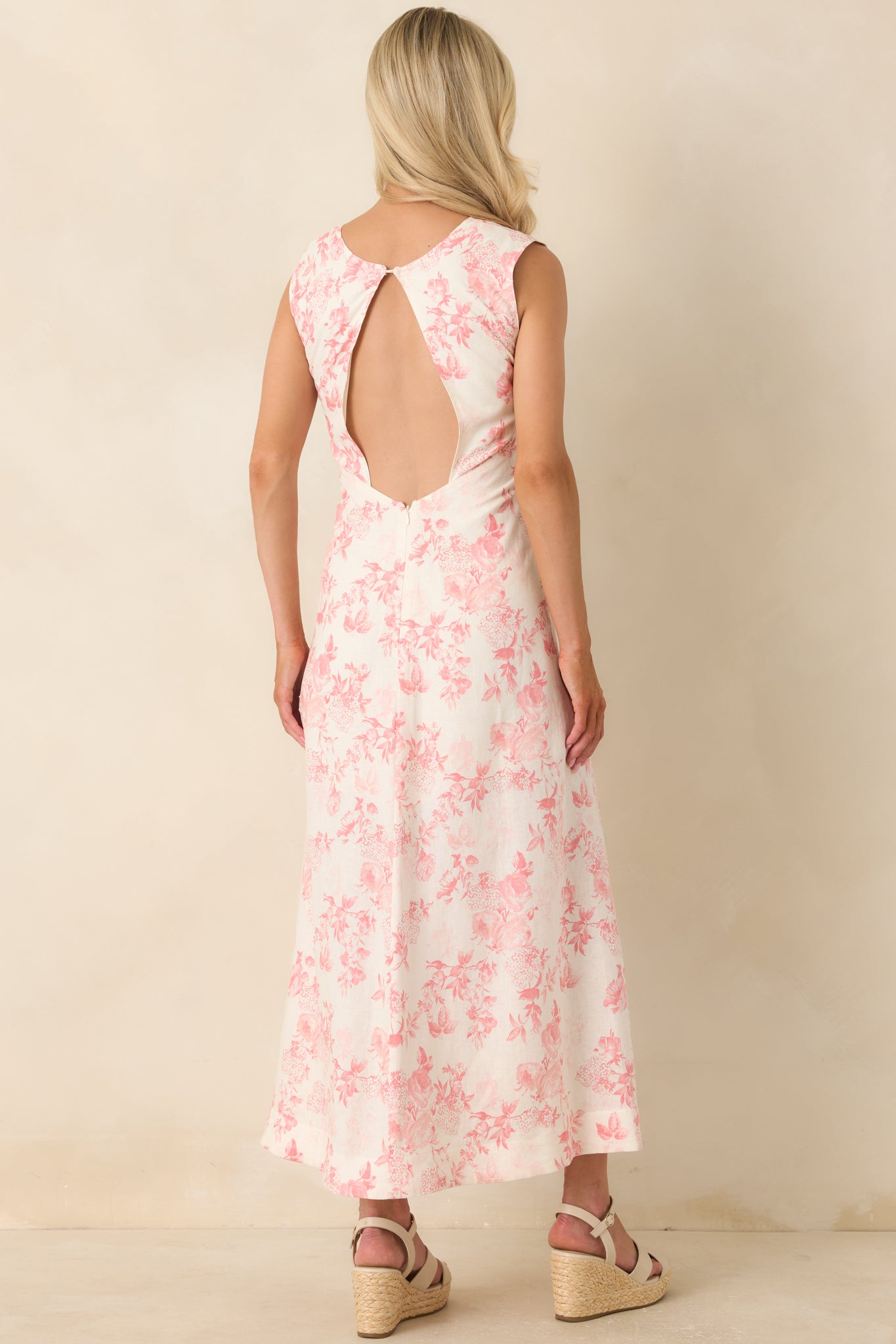 Back view of the ivory floral maxi dress featuring a large open back detail, single button closure at the neckline, concealed zipper closure, and flowing maxi-length skirt.