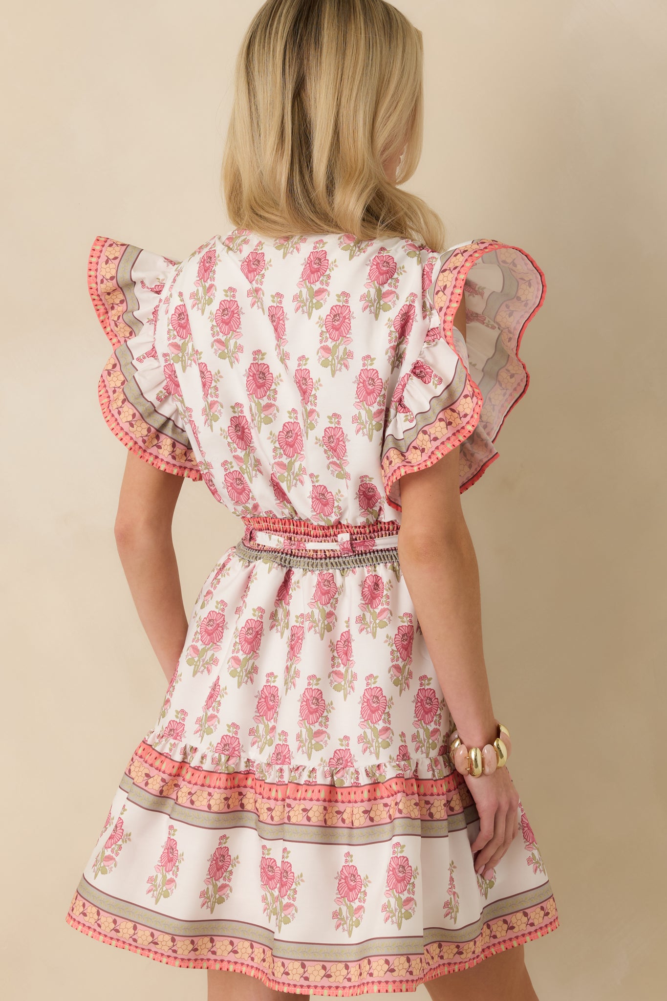 Back view of the white floral mini dress featuring an elastic waistband, tiered hem, and flutter sleeves.