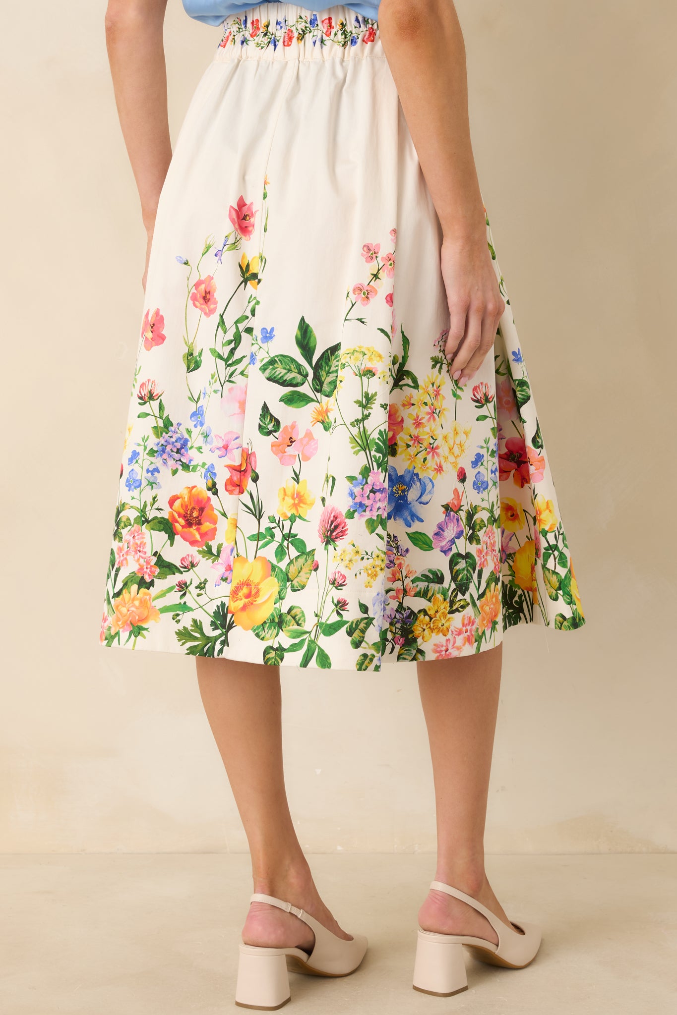 Back view of the ivory A-line midi skirt featuring an elasticized waistband and floral print accent at the hem.