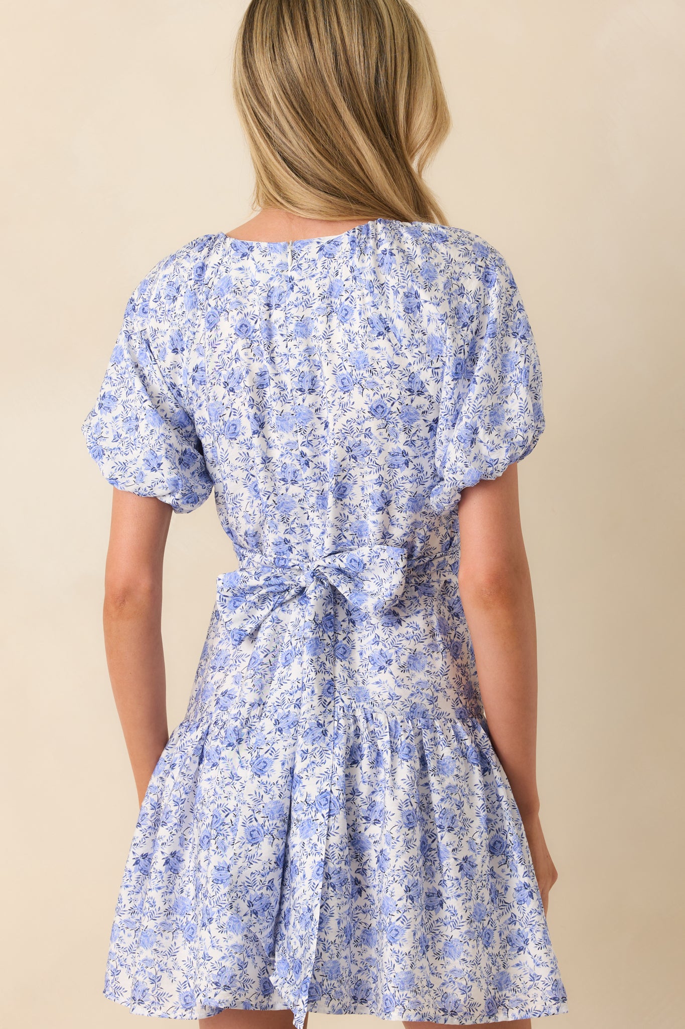 Back view of the dress featuring the attached self-tie bow at the waist, hidden back zipper, and continuation of the floral print.
