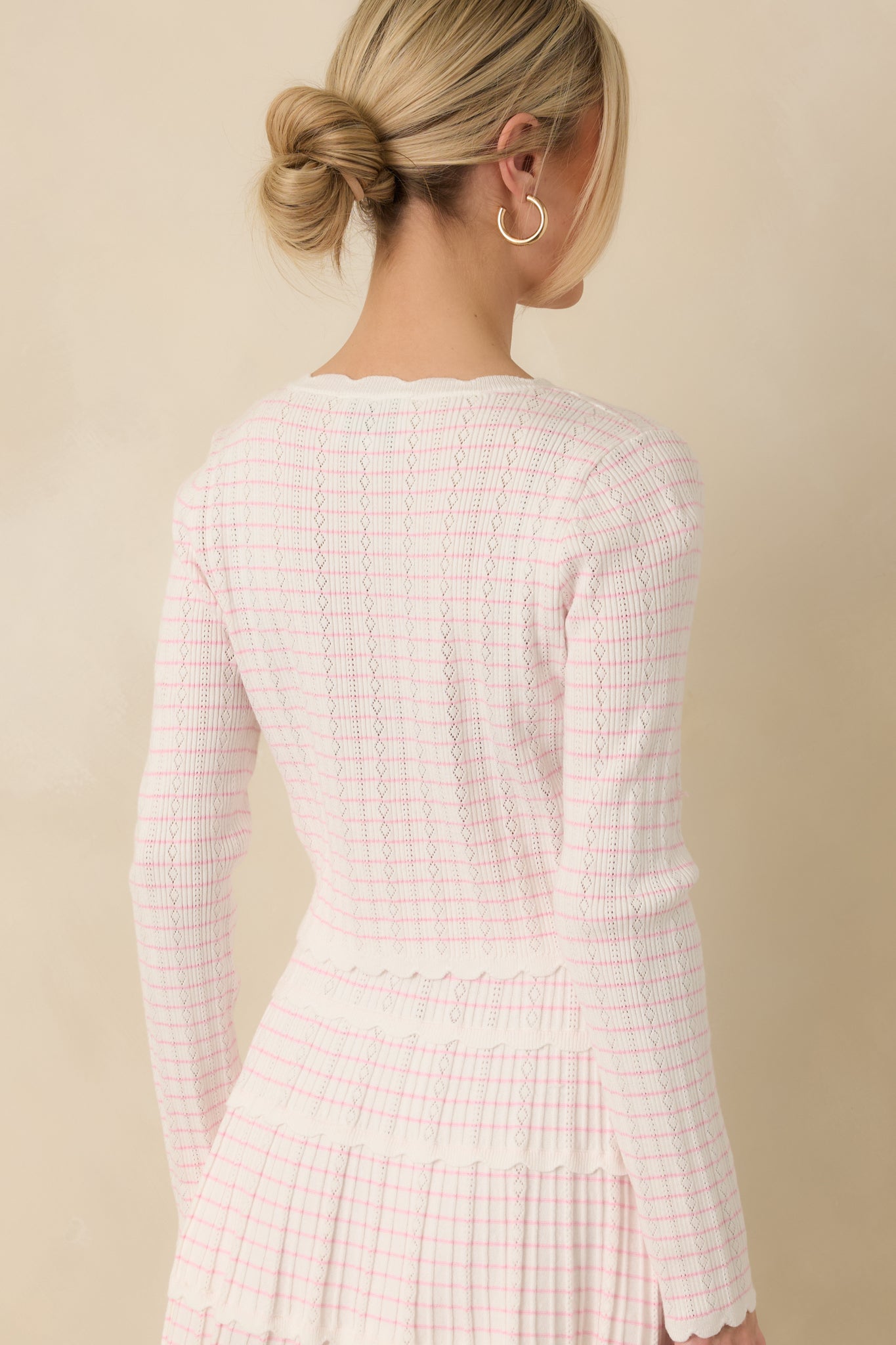 Back view of the white cardigan featuring the pink stripe pattern and a smooth knit finish.