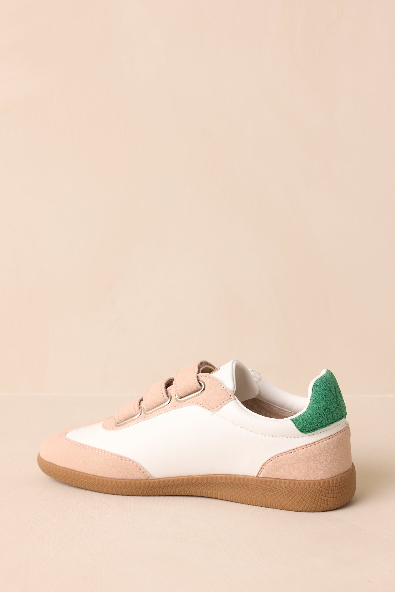 Back view of the low-top sneakers focusing on the green suede heel tab and clean ivory rear panel construction.