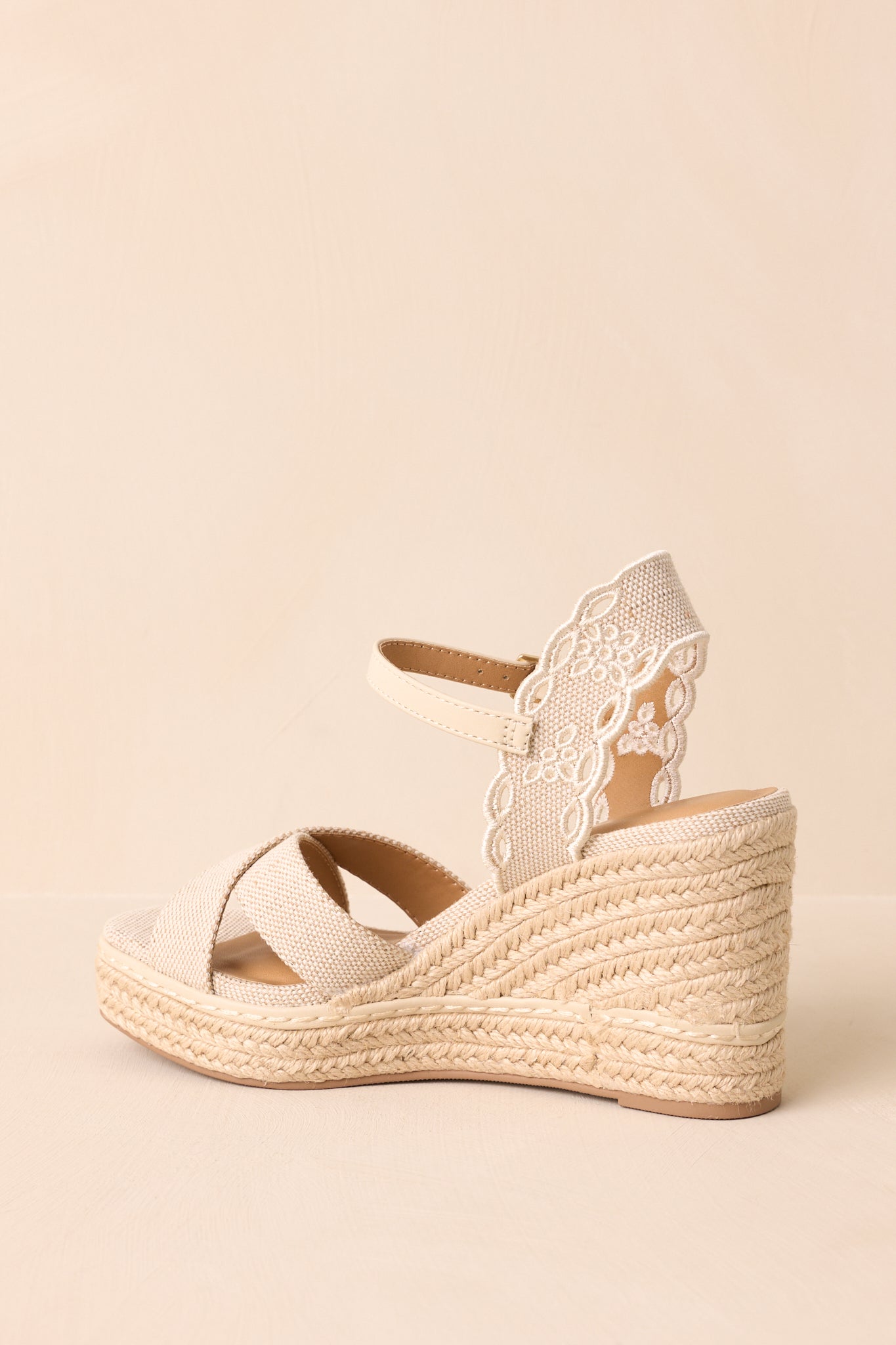 An angled back view of the wedges, focusing on the embroidered heel strap and jute-covered wedge heel.