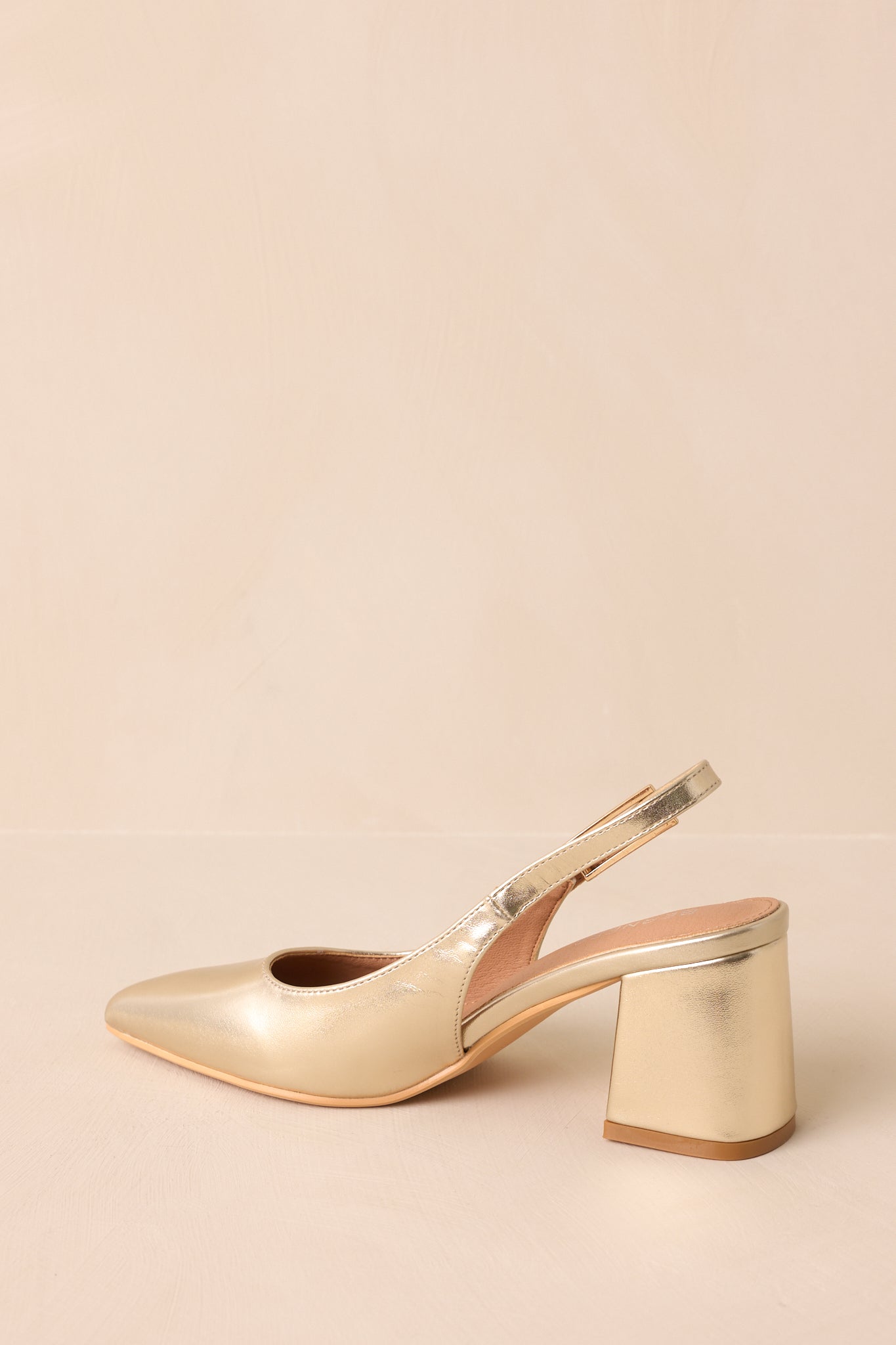 A back view of the gold heels highlighting the block heel and slingback strap.