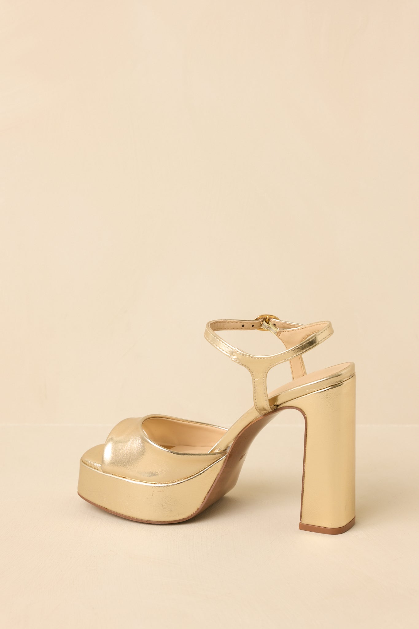 Back view of gold platform heels highlighting ankle strap, block heel, and durable outsole
