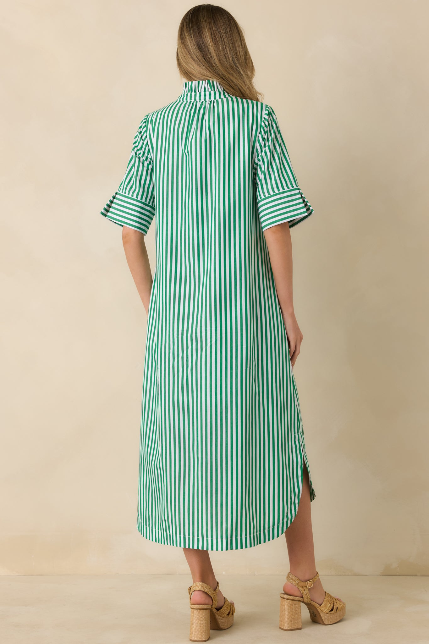 Back view of green striped midi shirt dress showing the flowy skirt and curved shirttail hem.