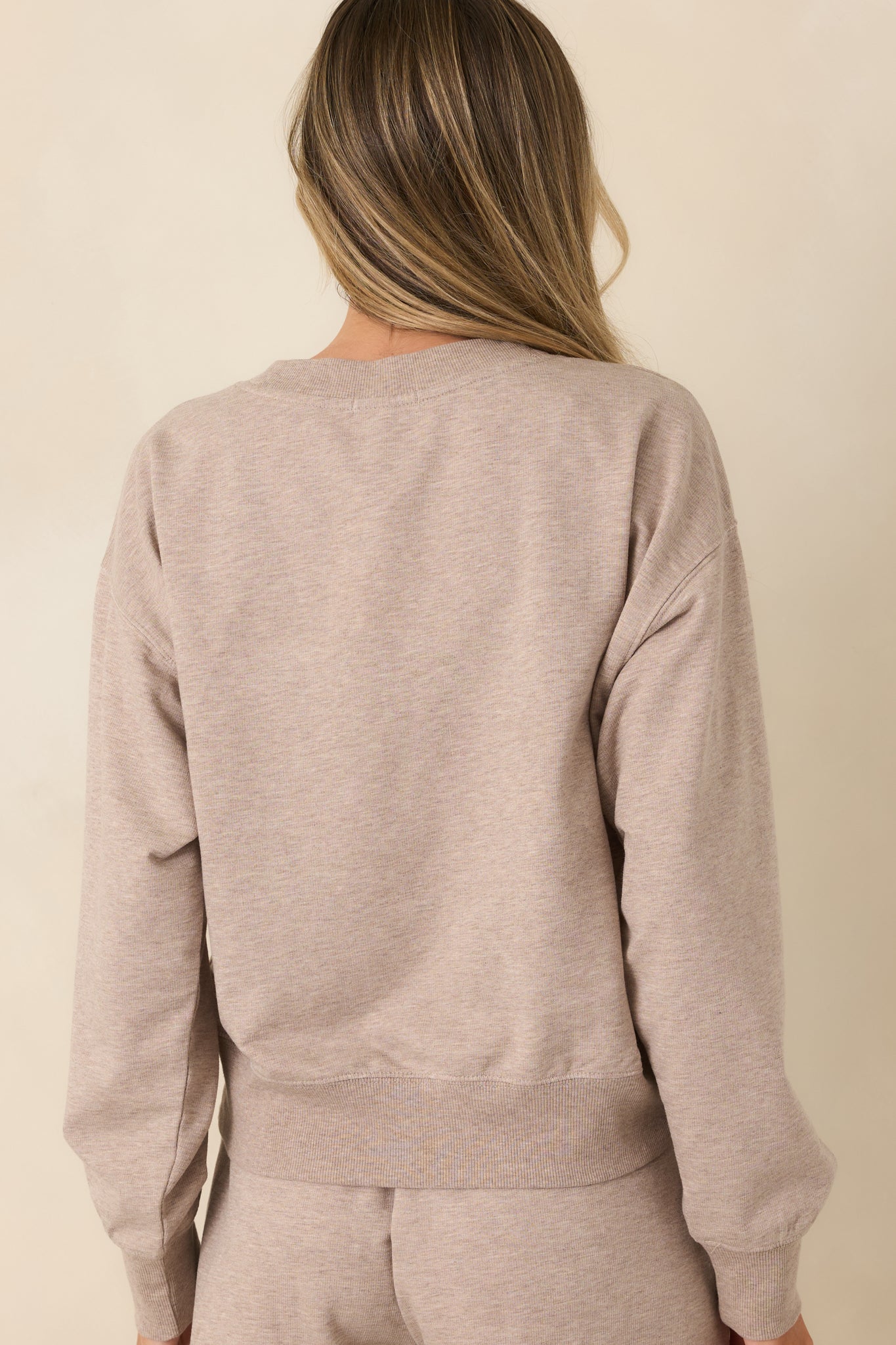 Back view of the oversized heather beige French terry top featuring relaxed shoulders and long sleeves.