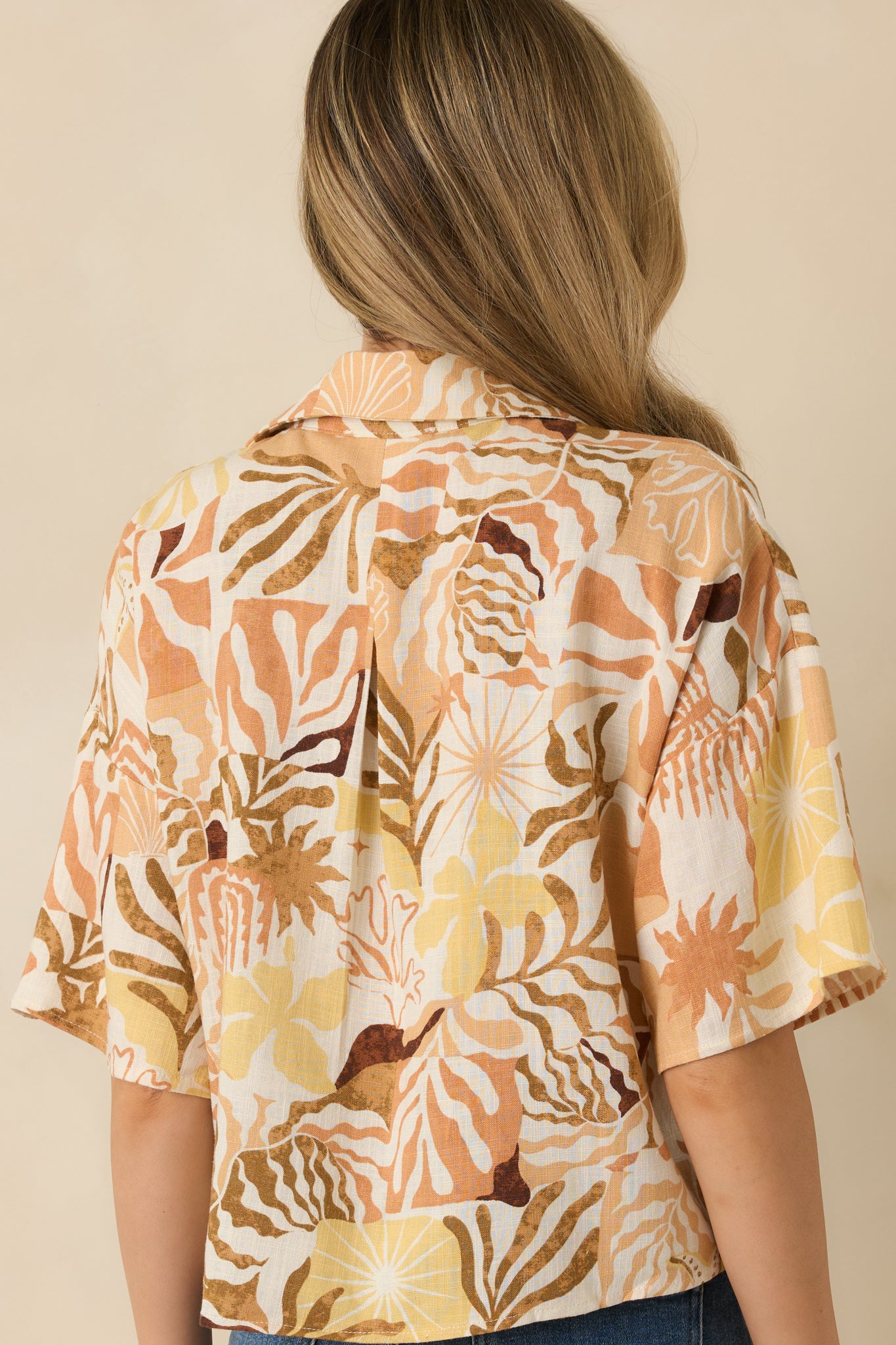 Back view of tan tropical print top highlighting relaxed fit and lightweight woven material.