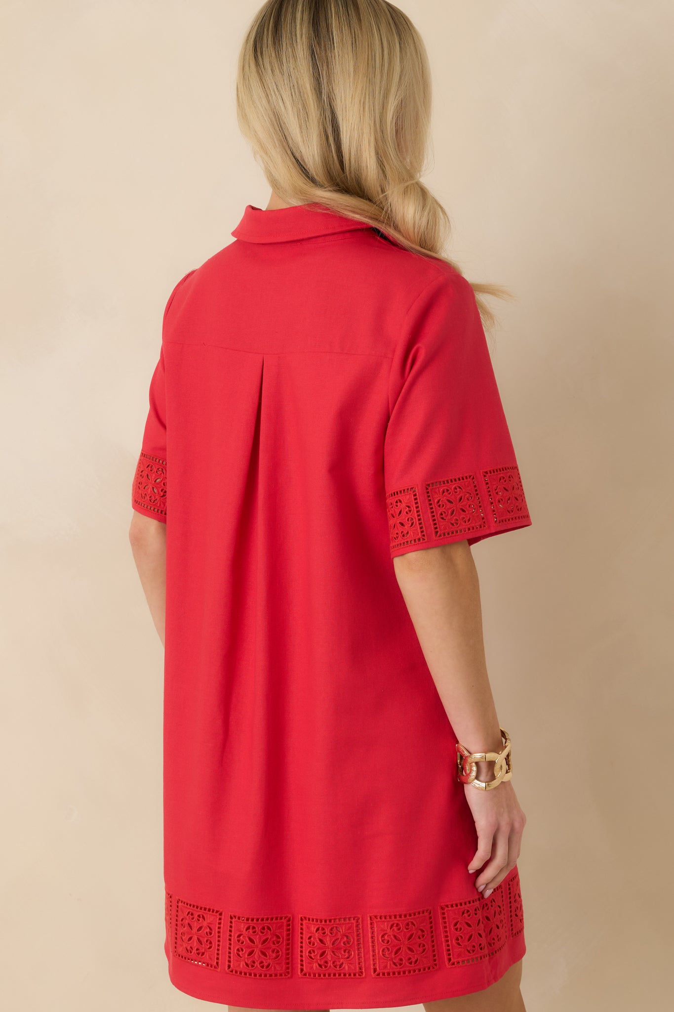 Back view of the red mini dress highlighting the back pleat, smooth fabric, and structured mini-length silhouette.