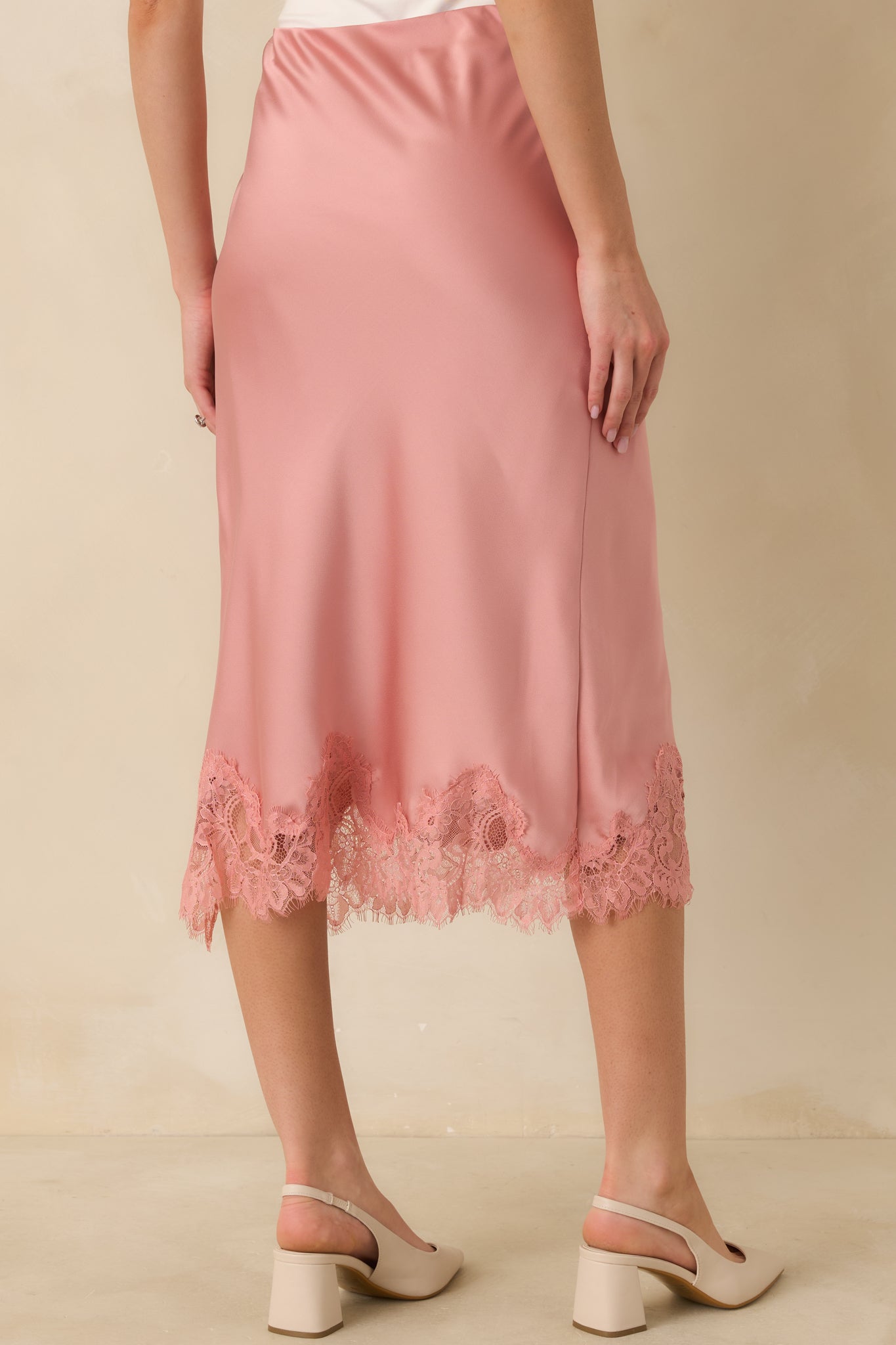 Back view of the blush satin midi skirt highlighting the elastic waistband and clean back silhouette.