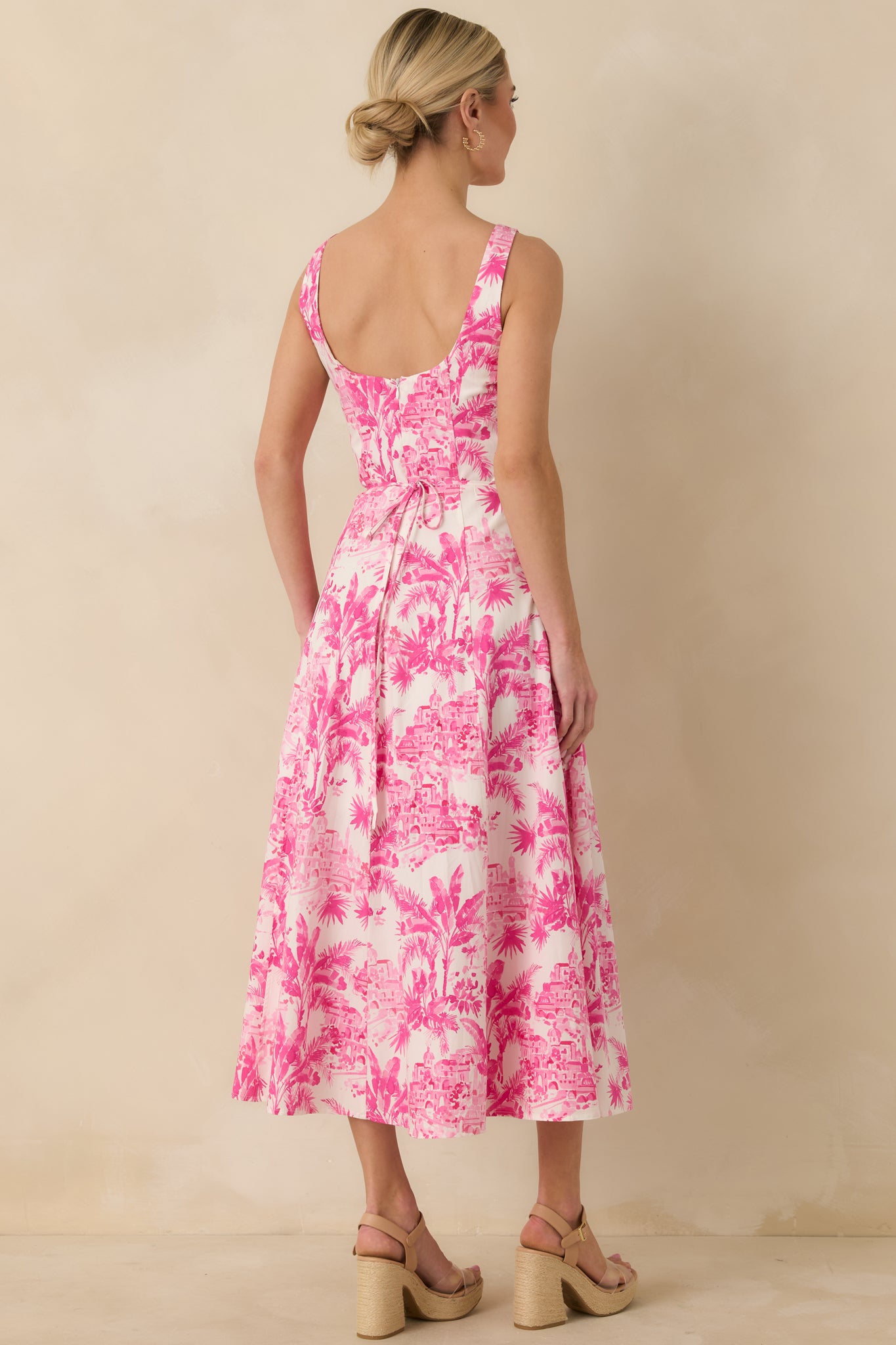 Back view of the hibiscus pink midi dress highlighting the open back, adjustable self-tie closure, and flowing skirt.