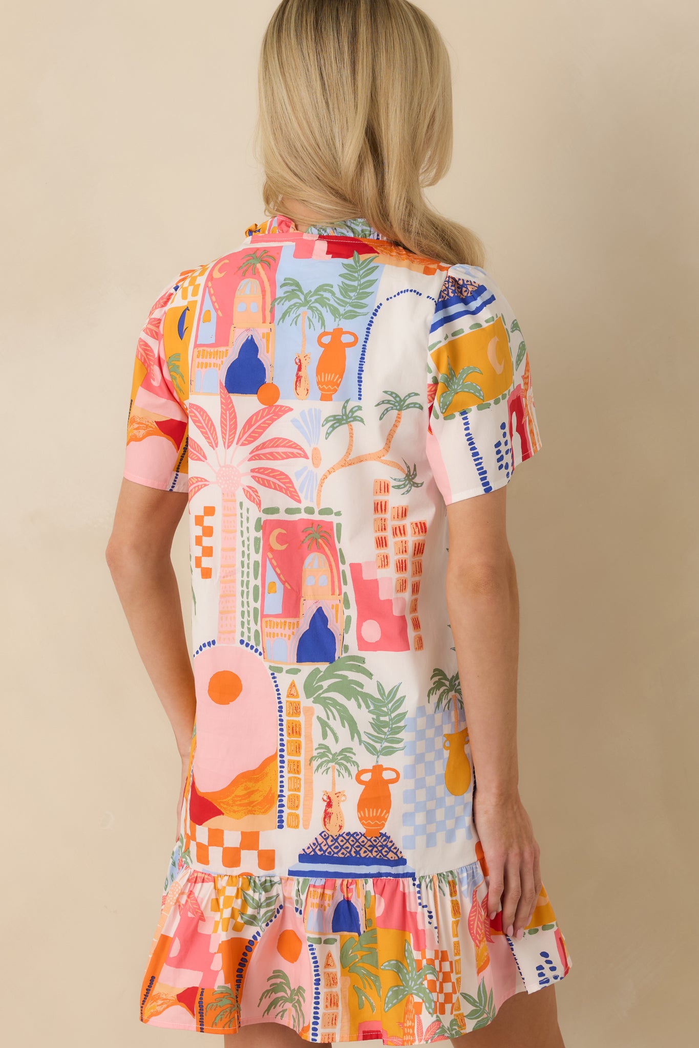 Back view of the orange and pink mini dress highlighting the relaxed A-line fit, tiered ruffle hem, and lightweight woven fabric.