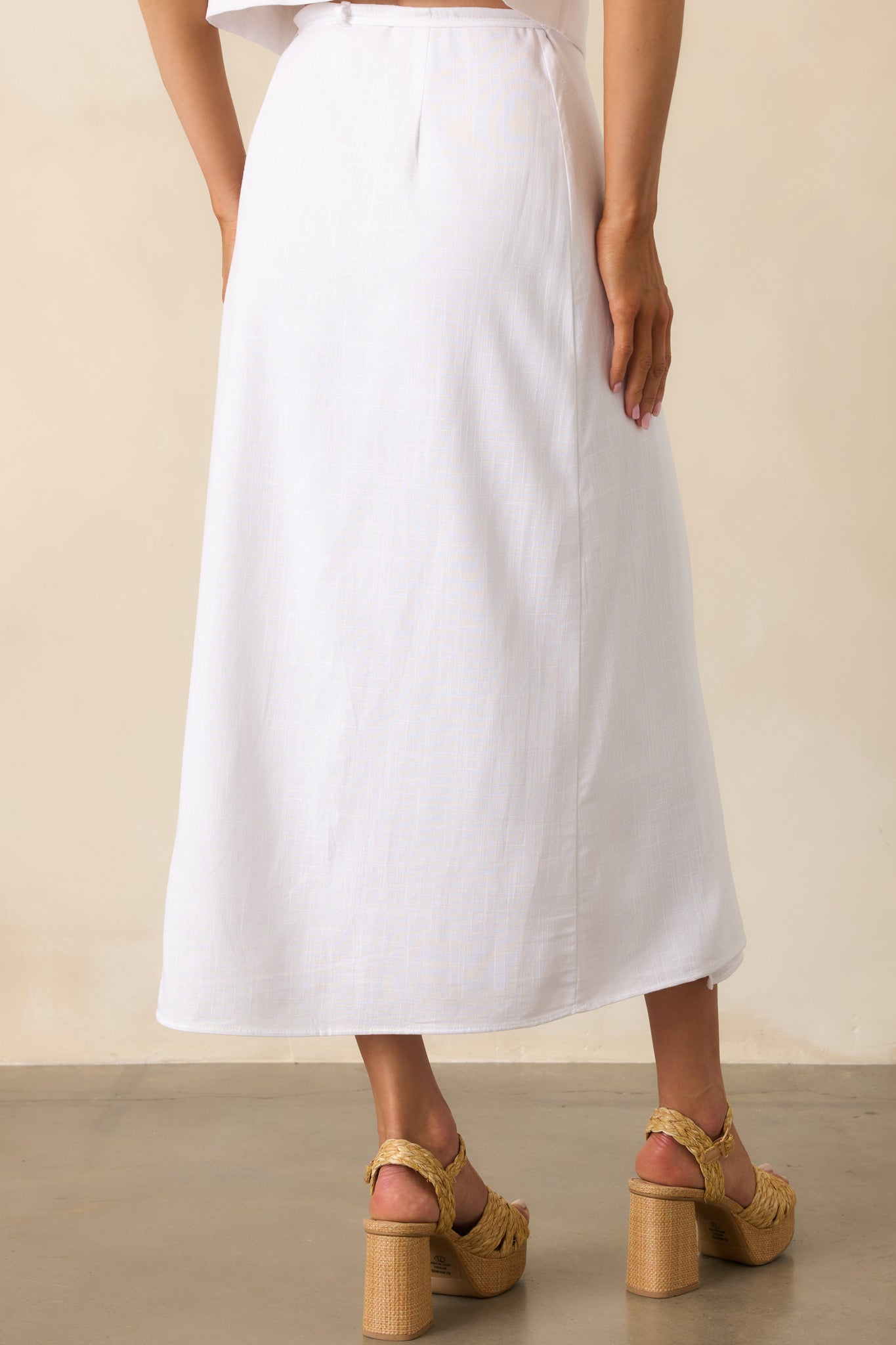 Full back view of the skirt highlighting the high rise waist, relaxed drape, and clean finish of the white lining from the back.