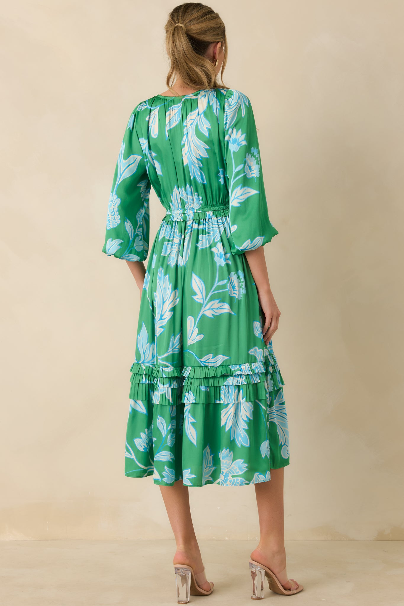 Back view of green and blue midi dress highlighting the relaxed fit, tiered ruffles, and balloon sleeve silhouette.