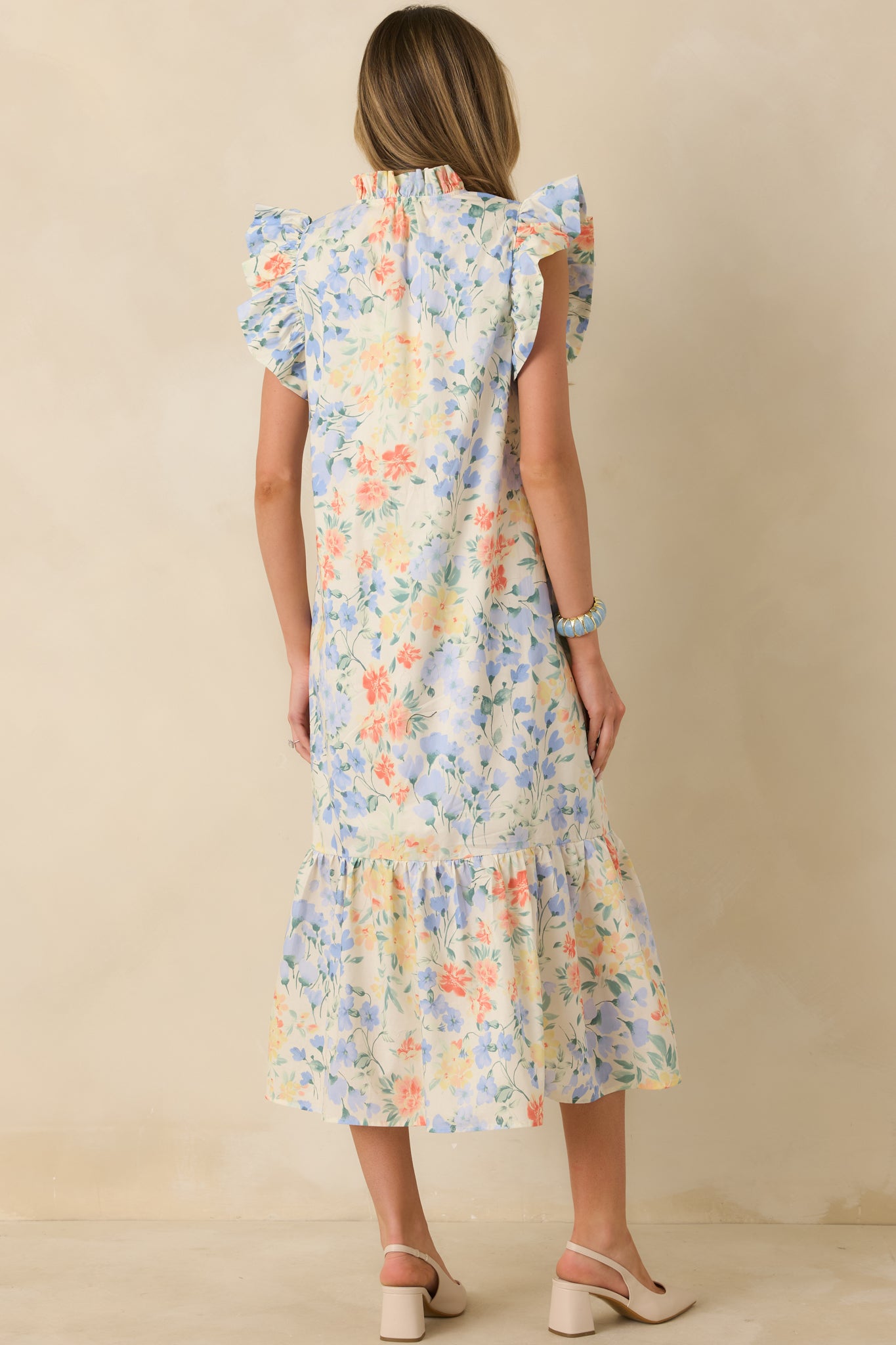 Back view of the ivory floral midi dress highlighting the relaxed flowy silhouette, tiered skirt, and soft cotton fabric.