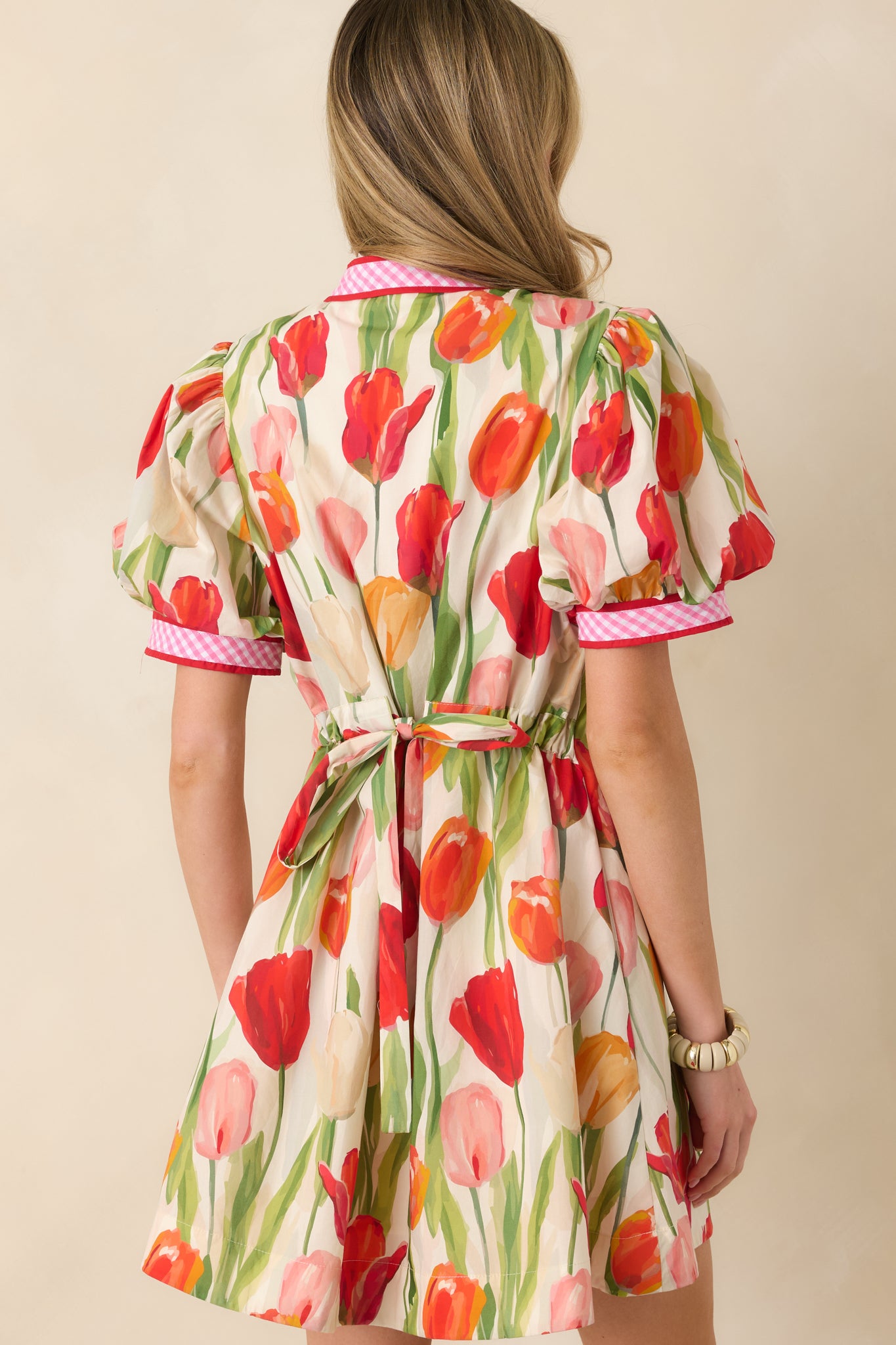 Back view of the red mini dress highlighting the tied waist, puff sleeves, and flowing skirt.